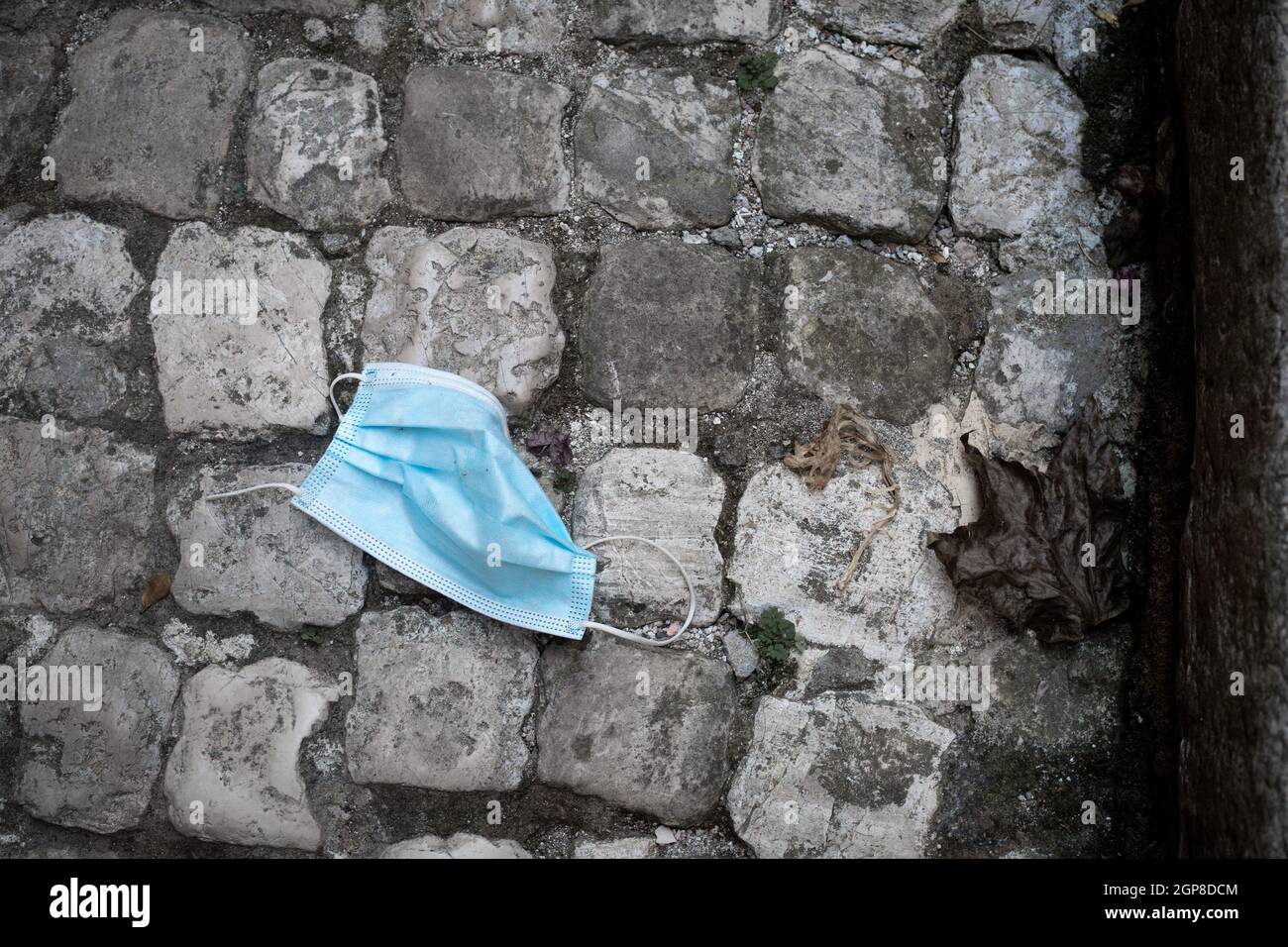 Image horizontale.Utilisé le mât médical bleu FFTP-2 s'est fronci sur le pavé gris pavé de pavés.Noir et blanc avec bleu.Image de contraste.Pollution Banque D'Images
