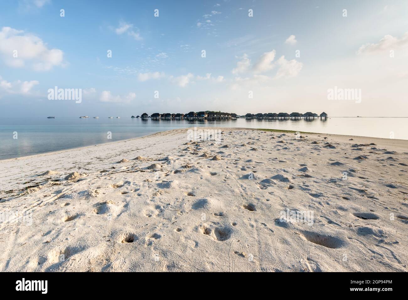 Bungalow sur l'eau des Maldives sur l'océan paysage d'eau. Crabes trous sur le sable de la plage au premier plan. Banque D'Images