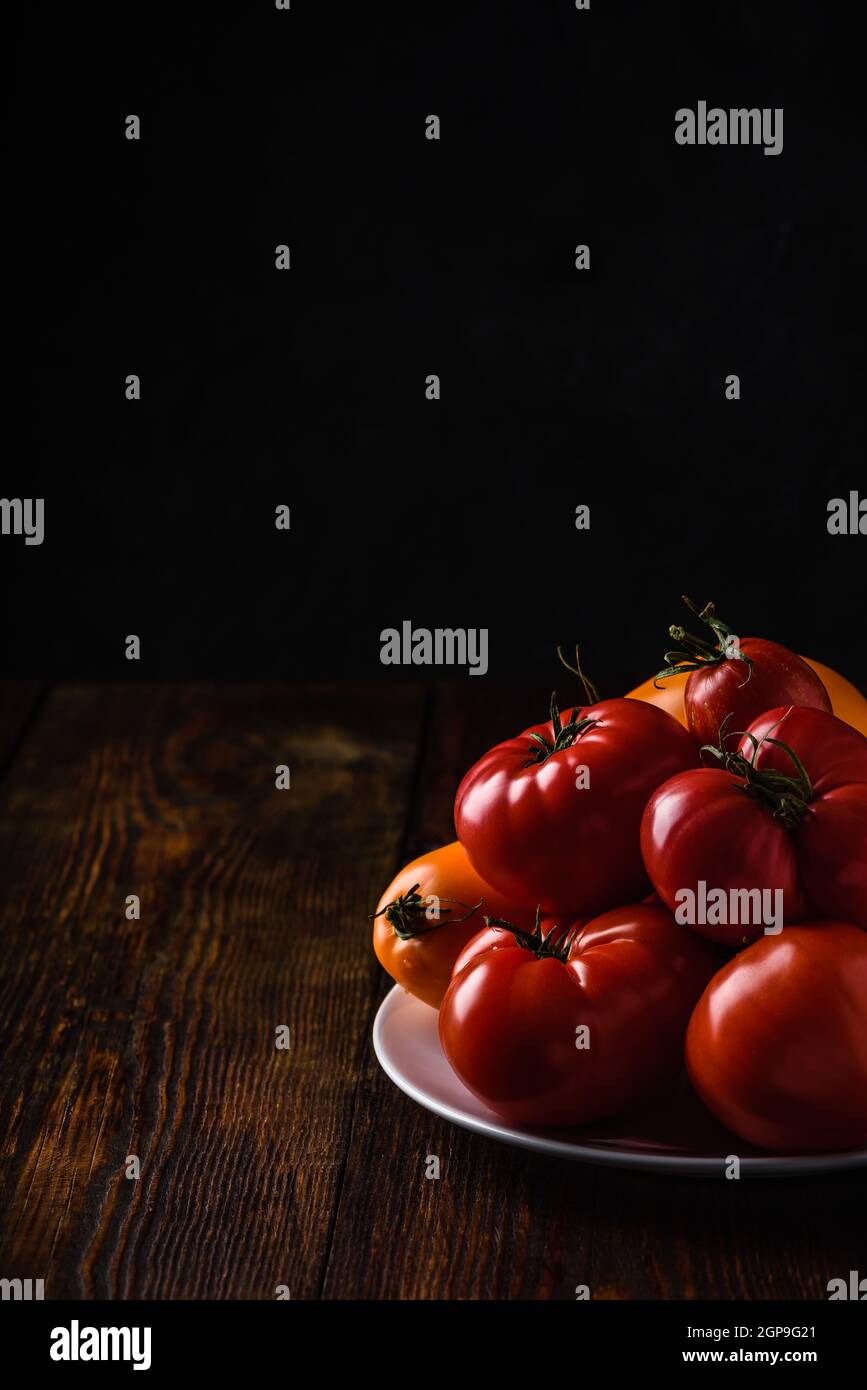 Tomates fraîches rouges et jaunes sur plaque blanche sur bois surface Banque D'Images