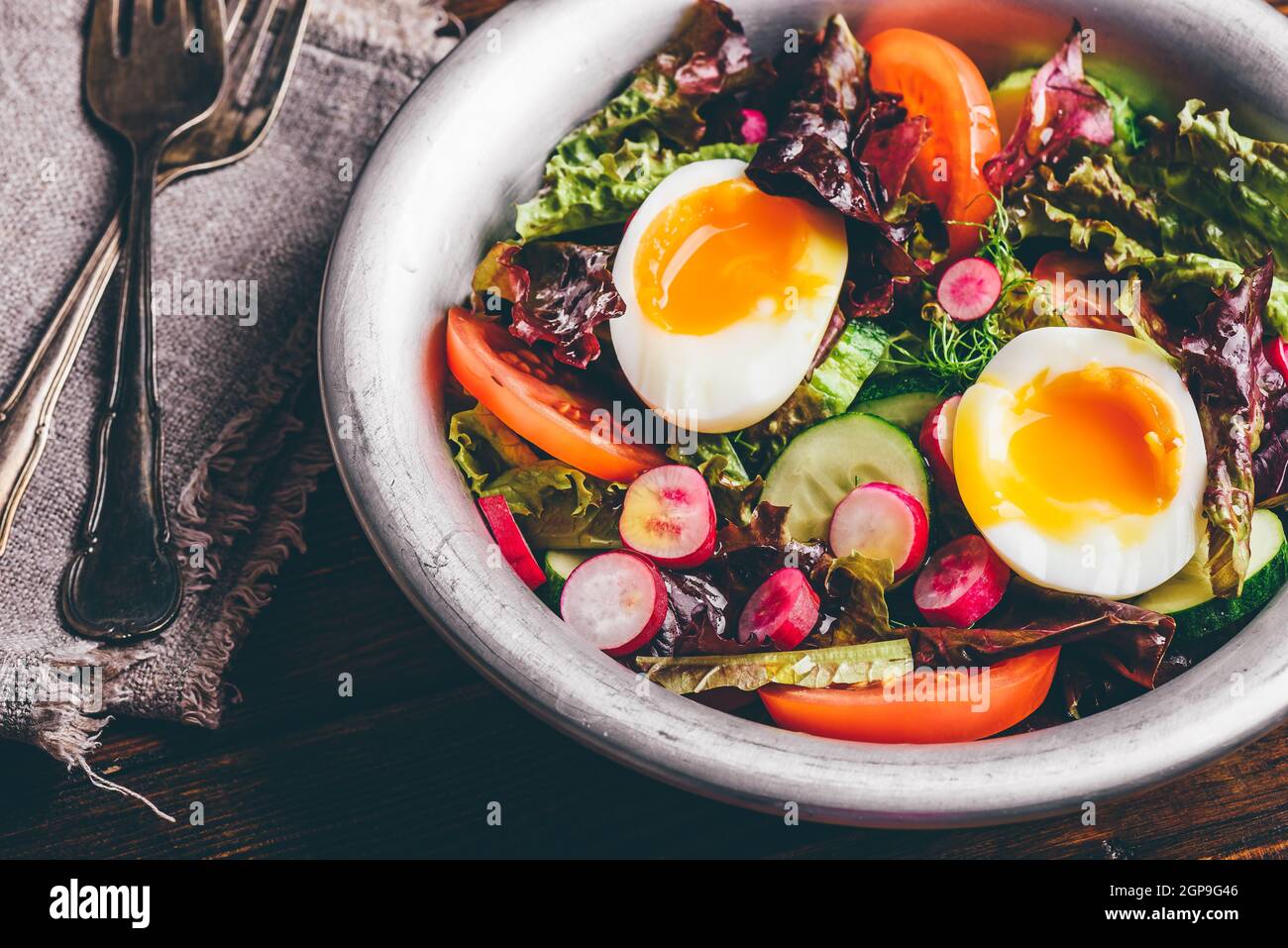 Salade de printemps frais et tomates, radis, concombre, laitue frisée rouge et d'œufs durs dans bol en métal Banque D'Images
