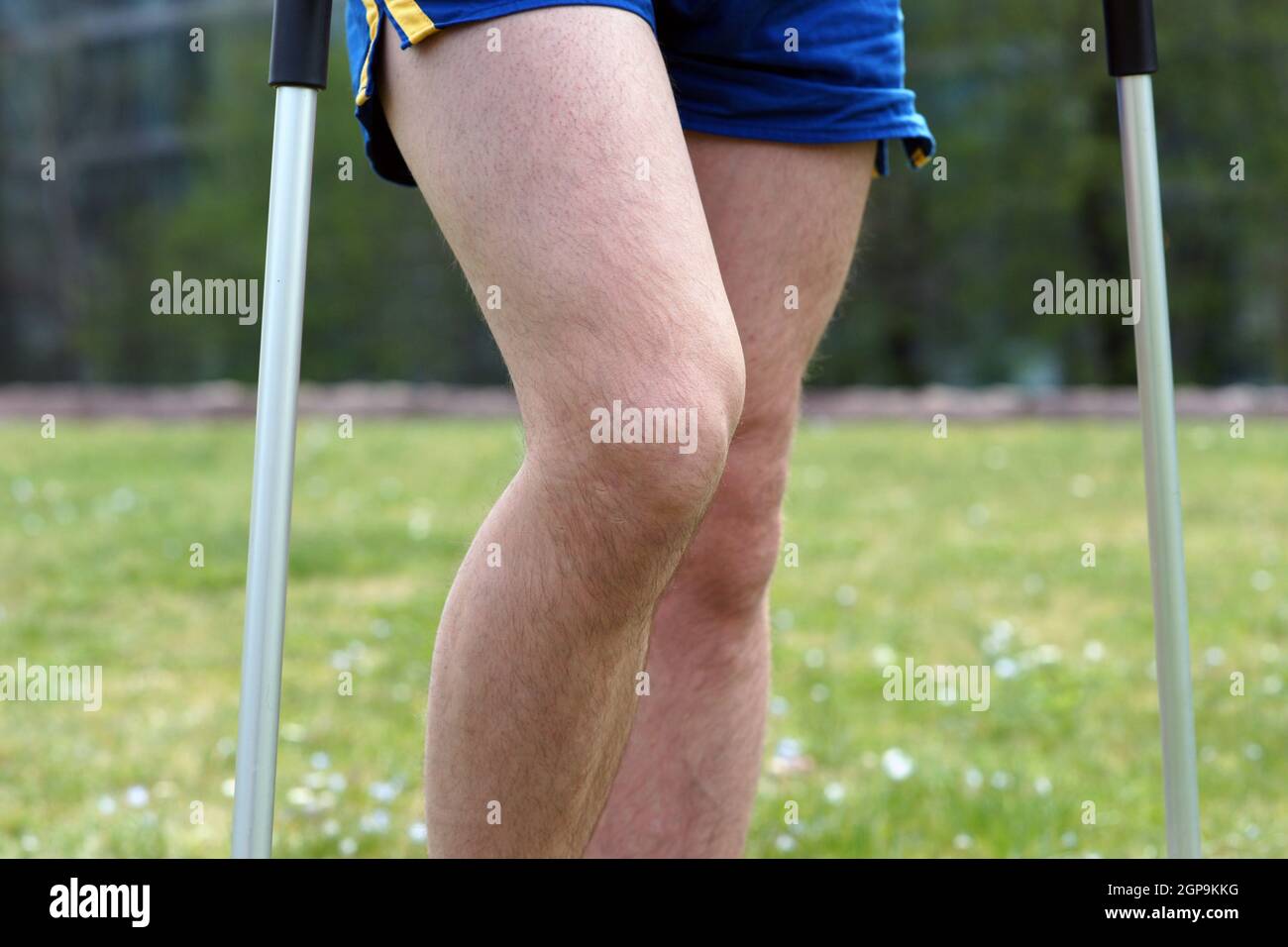 Un jeune homme de sport marche dans le parc de la ville avec des béquilles après un accident sportif Banque D'Images