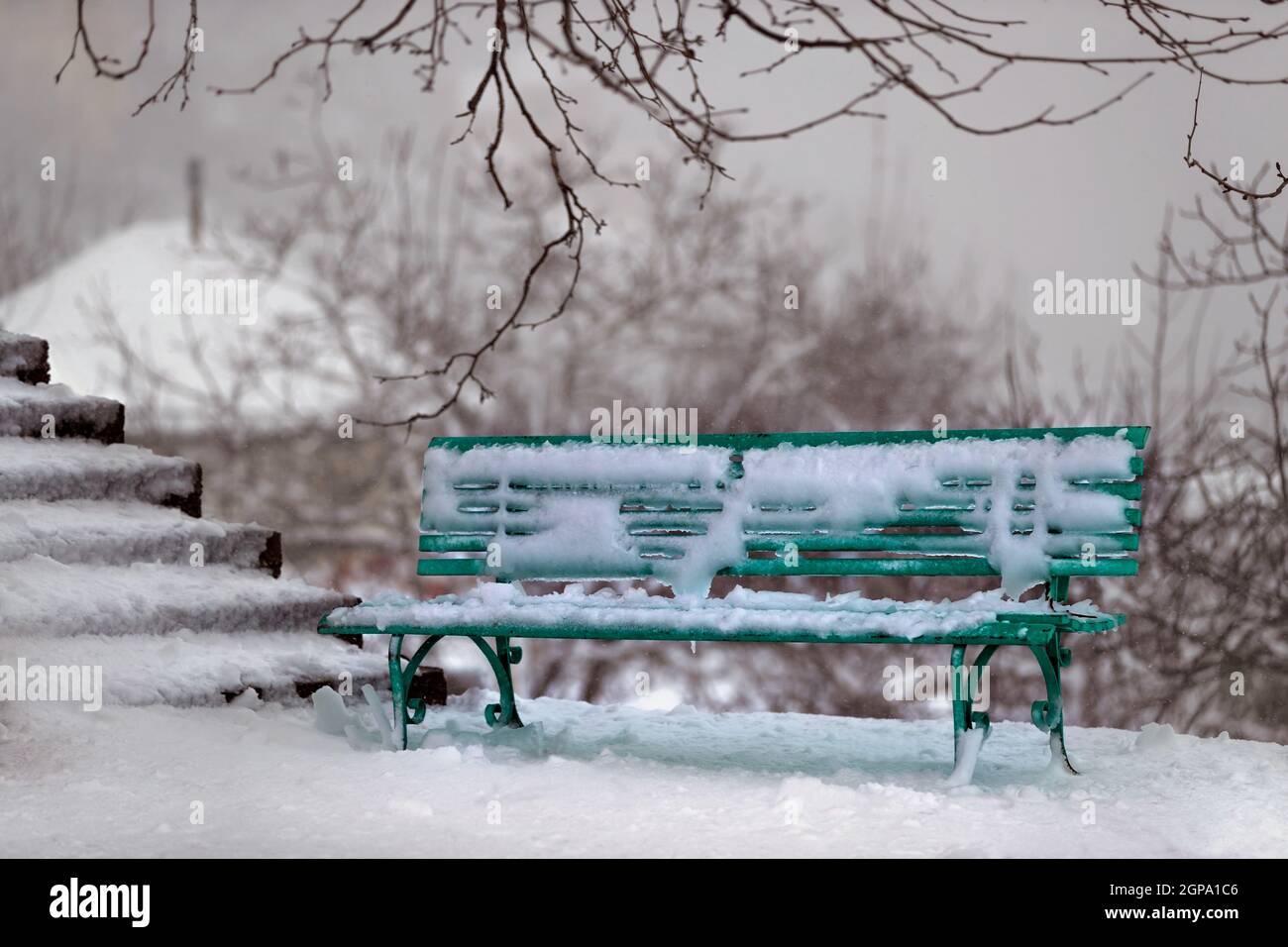 Scène d'hiver. Banc vert près des escaliers dans le parc couvert de neige. En hiver, à l'extérieur. Banque D'Images