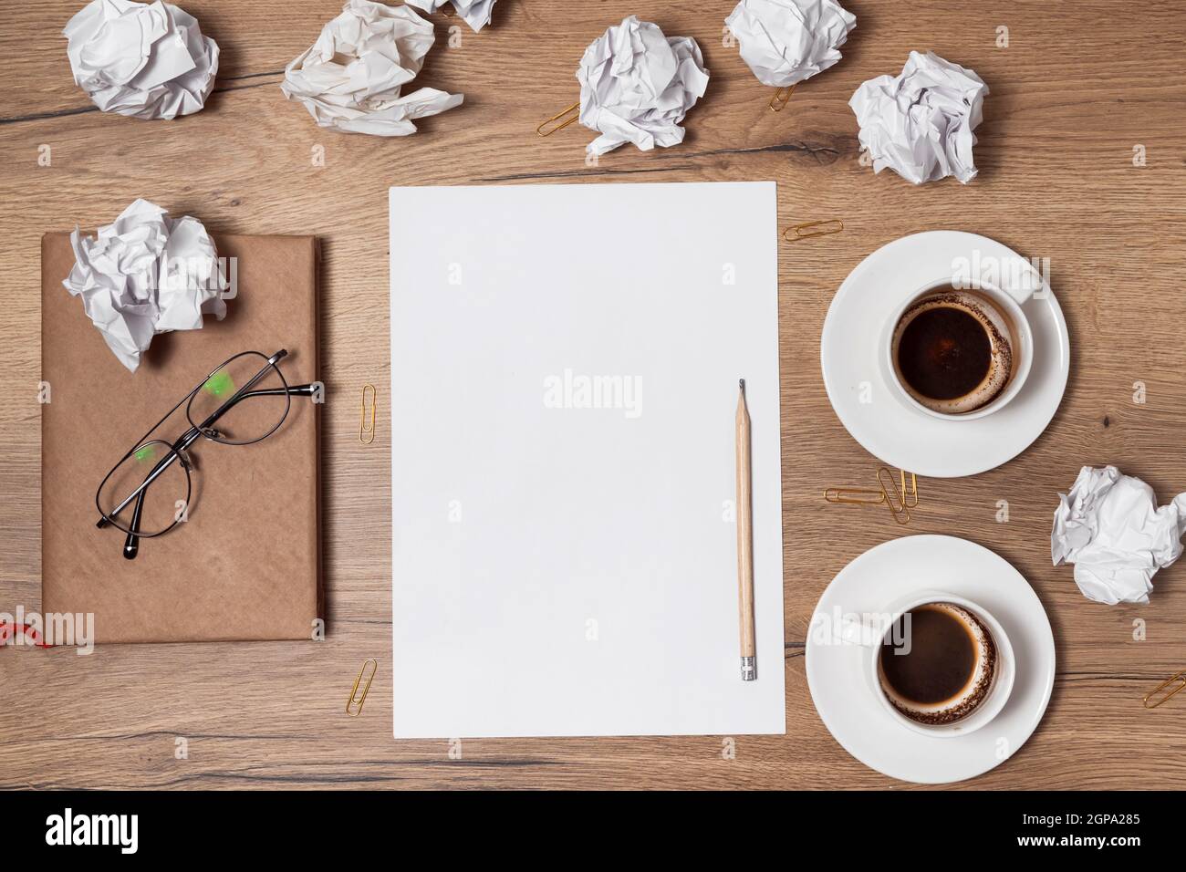 Des papiers froissés éparpillés, des tasses vides de café sur la table d'un travailleur de la création. Crise créative. Concept de stress, de troubles de santé mentale et de manque de moi Banque D'Images