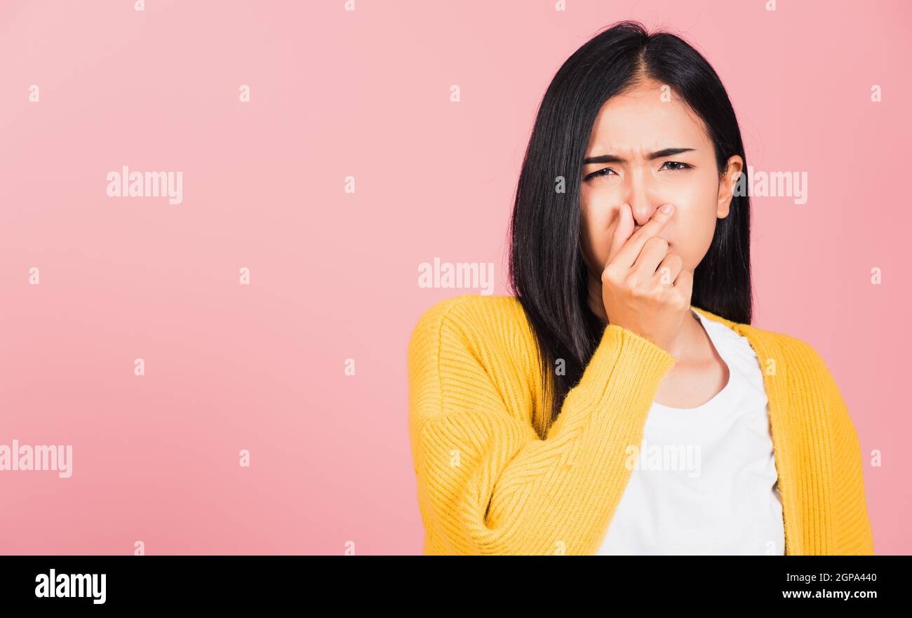 Asiatique belle jeune femme malheureux ce qu'une expression de dégoût d'odeur pinçant le nez avec les doigts. Les femmes ont quelque chose de mauvais odeur situation, stu Banque D'Images