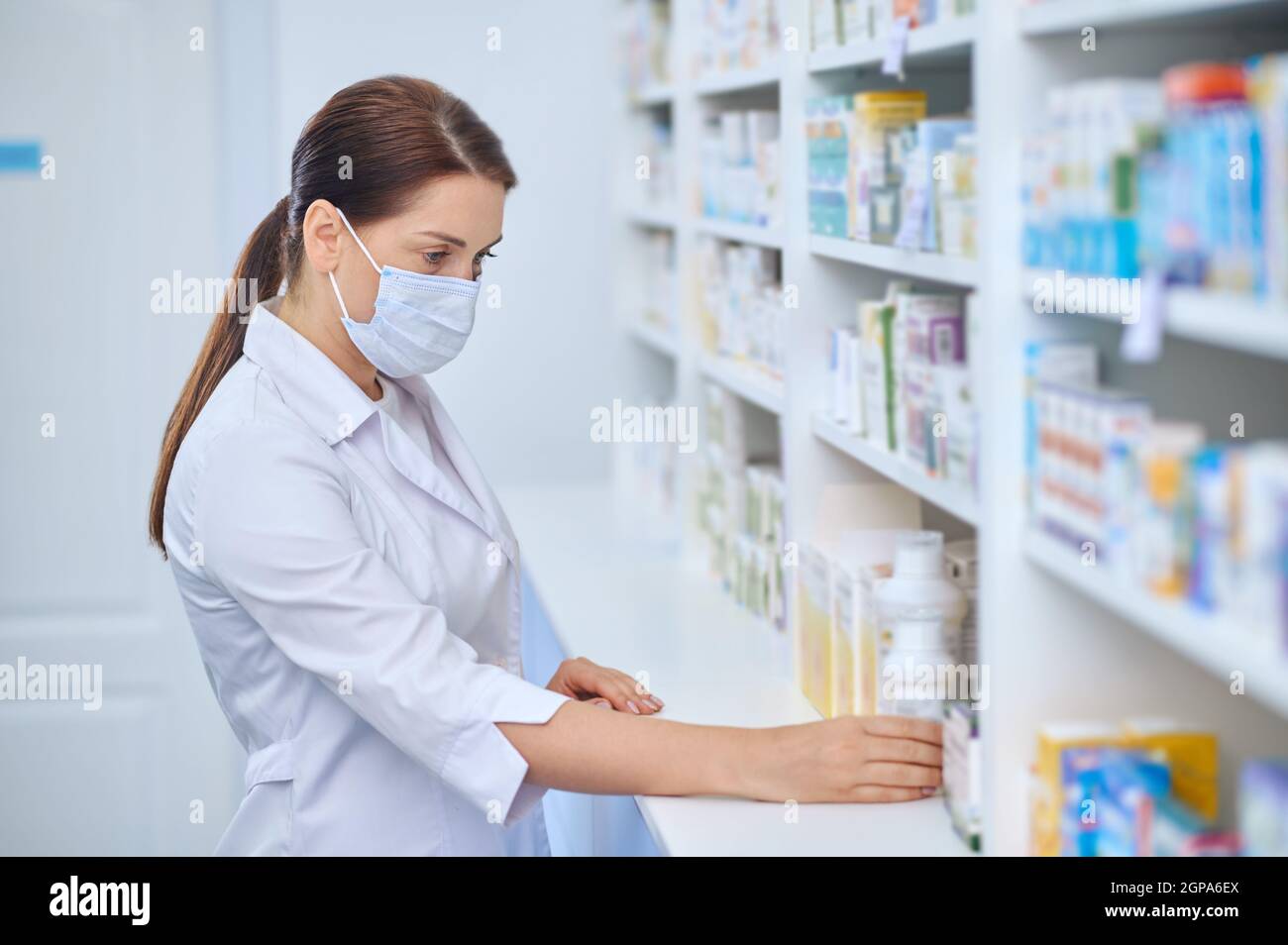 Femme intéressée pharmacien examinant des médicaments sur des étagères Banque D'Images