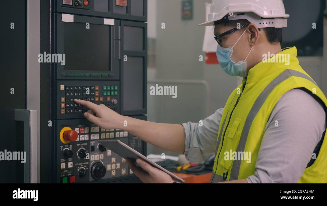 Ouvrier d'usine asiatique travaillant la programmation automatique CNC de commande de fraisage centre de l'industrie des machines pour la fabrication d'ateliers d'outillage Banque D'Images
