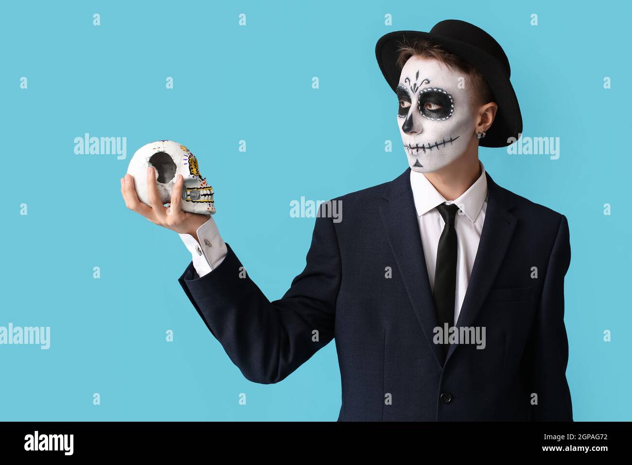 Jeune homme au visage peint et au crâne de sucre pour la Journée des morts du Mexique (El Dia de Muertos) sur fond de couleur Banque D'Images