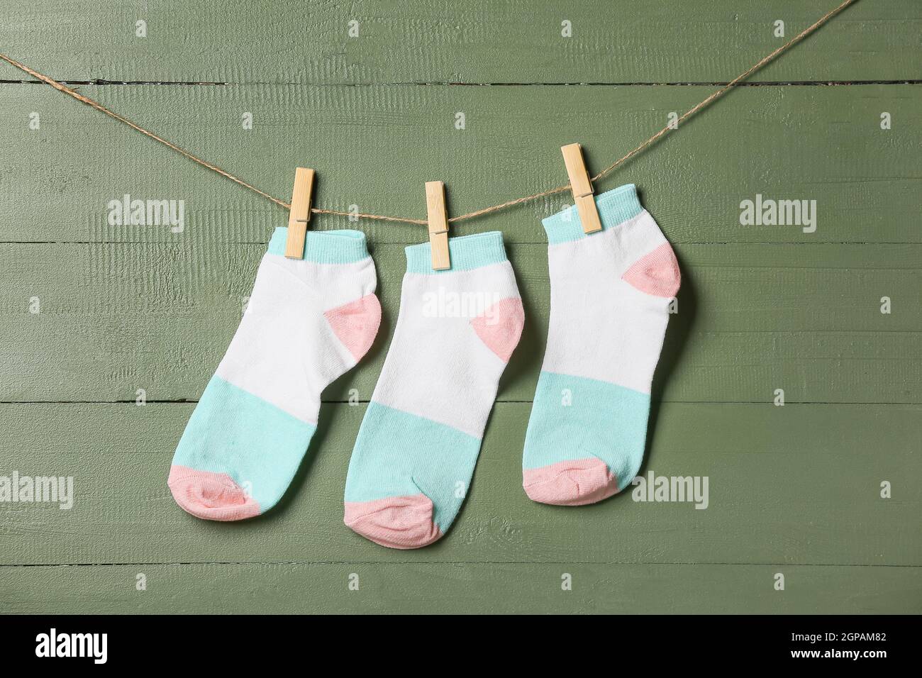 Trois chaussettes accrochées à la corde sur fond de bois vert Banque D'Images