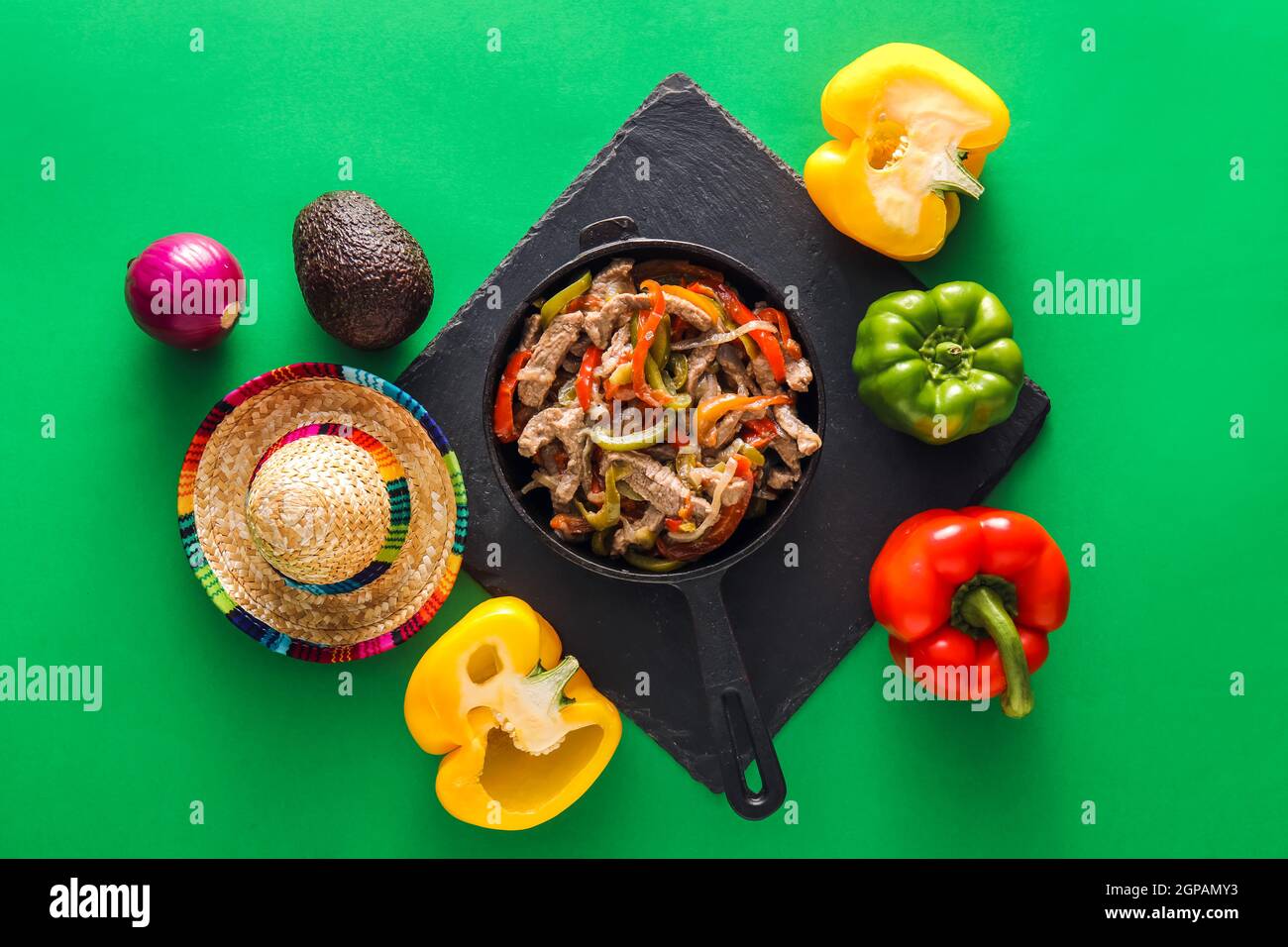 Composition avec de savoureux fajita, légumes et chapeau de sombrero sur fond vert Banque D'Images