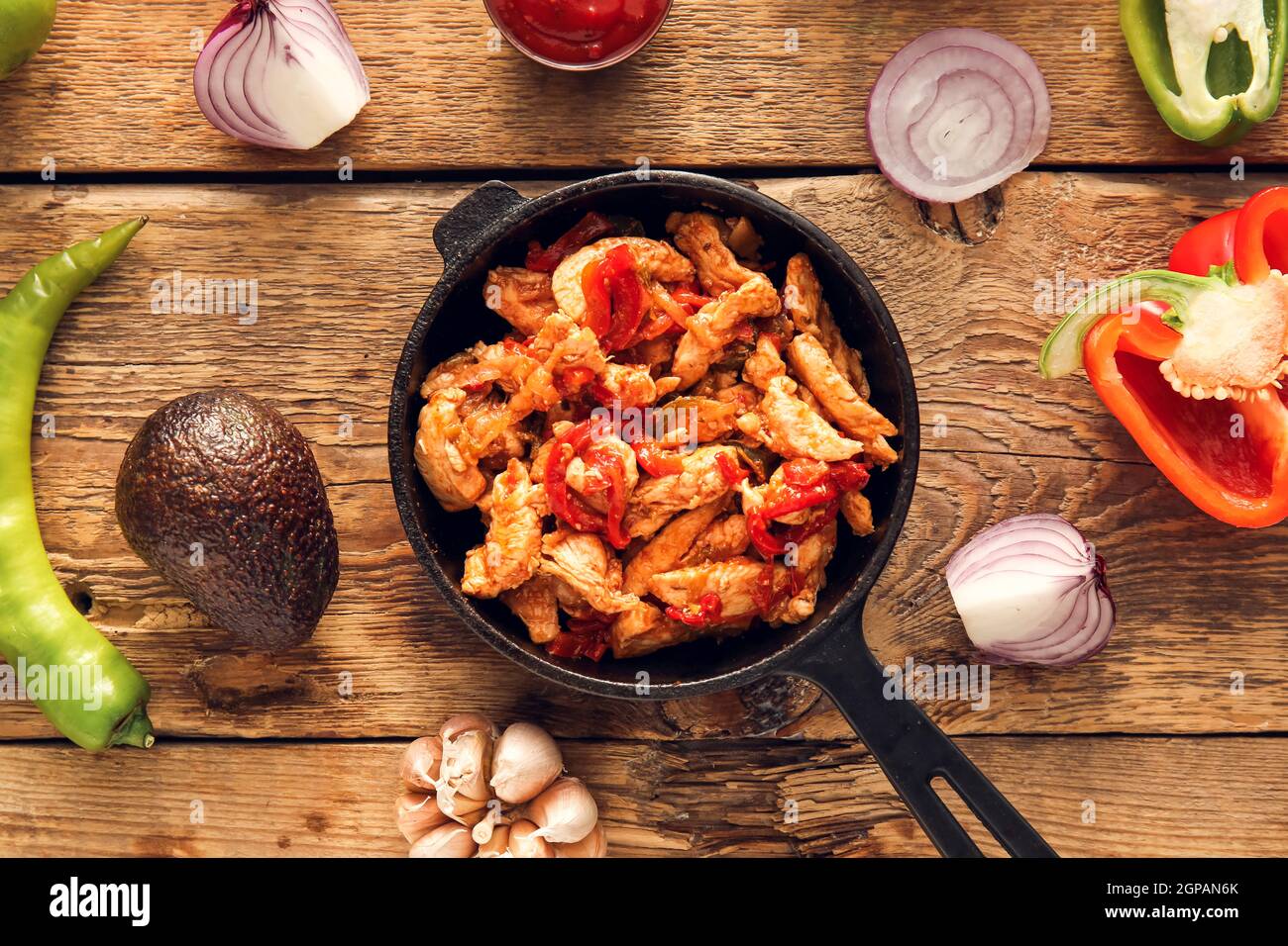 Poêle à frire avec de savoureux poulet Fajita et légumes sur fond de bois Banque D'Images