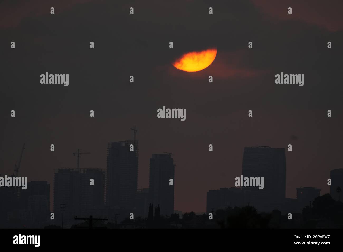 Le soleil se couche sur la ligne d'horizon du centre-ville dans un ciel sombre par des feux de forêt, le mardi 28 septembre 2021, à Los Angeles. Banque D'Images