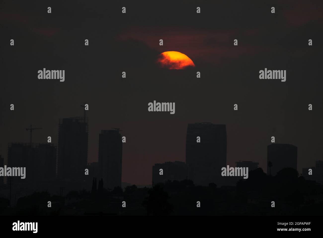Le soleil se couche sur la ligne d'horizon du centre-ville dans un ciel sombre par des feux de forêt, le mardi 28 septembre 2021, à Los Angeles. Banque D'Images