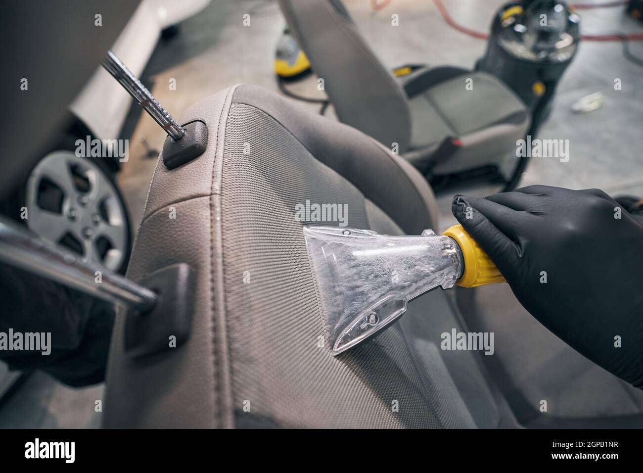 Nettoyage à l'aspirateur et séchage du siège en cuir par un technicien d'entretien automobile Banque D'Images