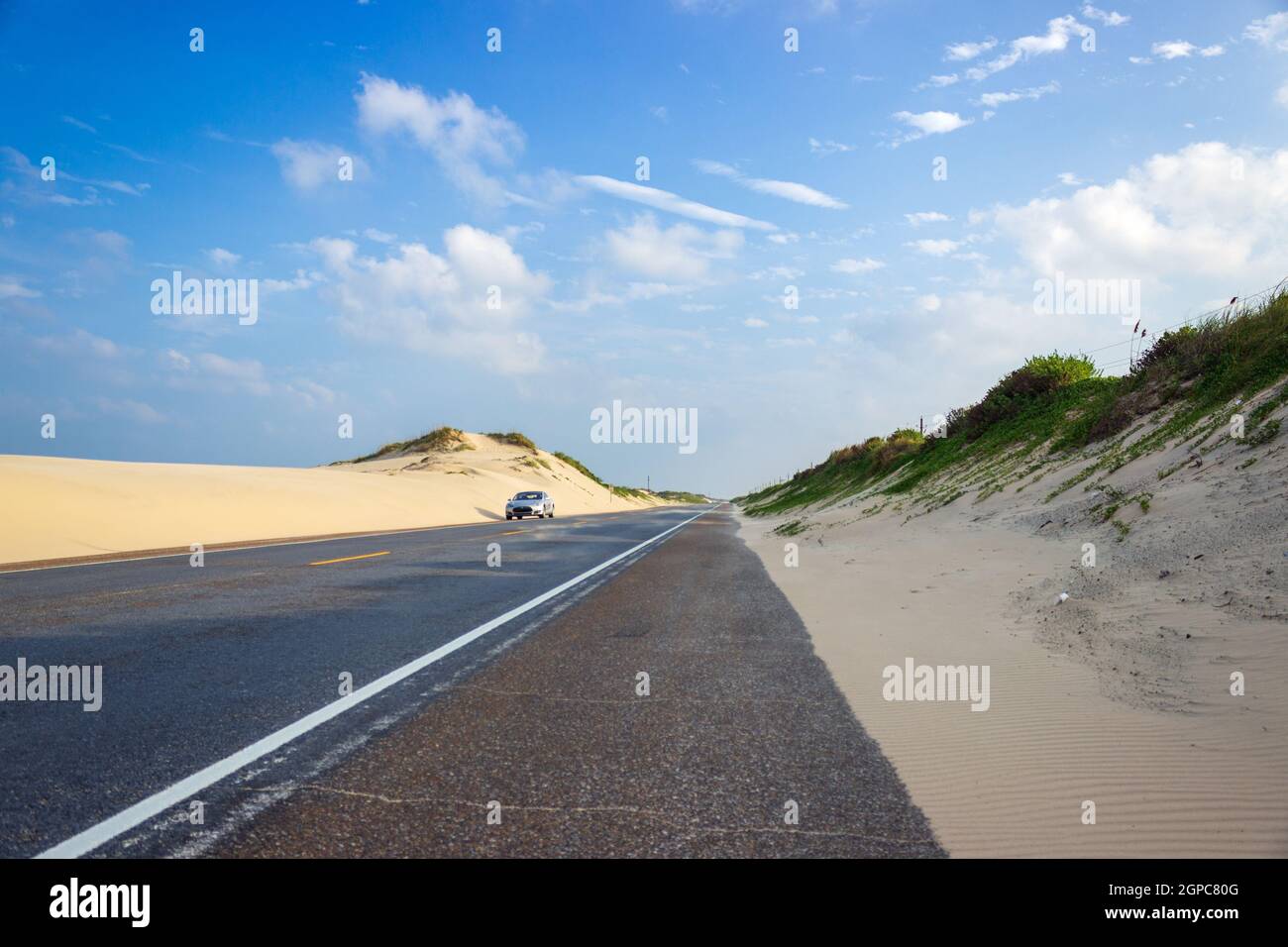 Un sliver 2014 Tesla Model S à côté des dunes de sable mouvantes de South Padre Island, Texas le long d'Ocean Boulevard. Banque D'Images