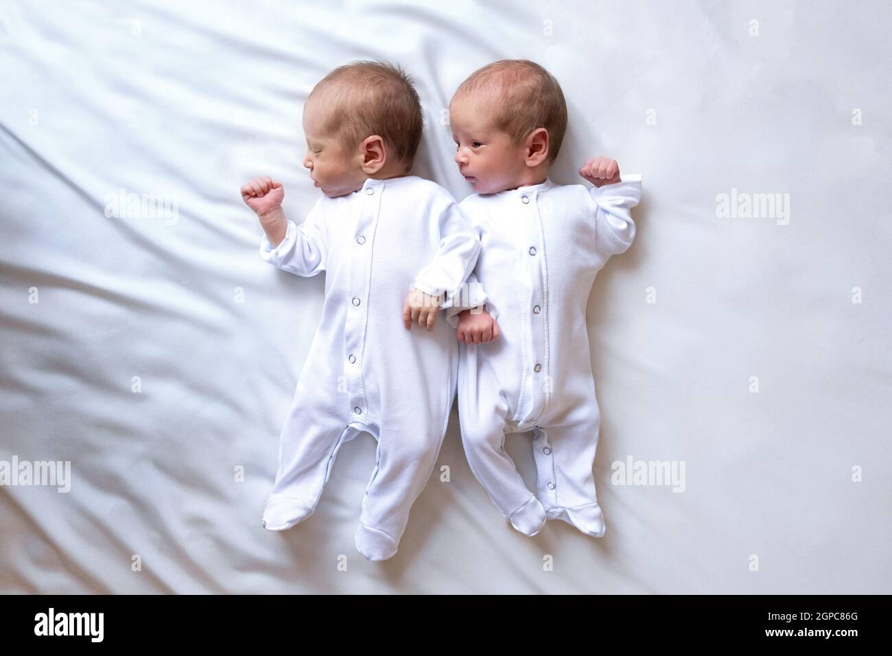 Nouveau Nes Jumeaux Sur Le Lit Dans Les Bras De Leurs Parents Sur Fond Blanc Style De Vie Emotions Des Enfants Grossesse Multiple La Grande Famille Photo Stock Alamy