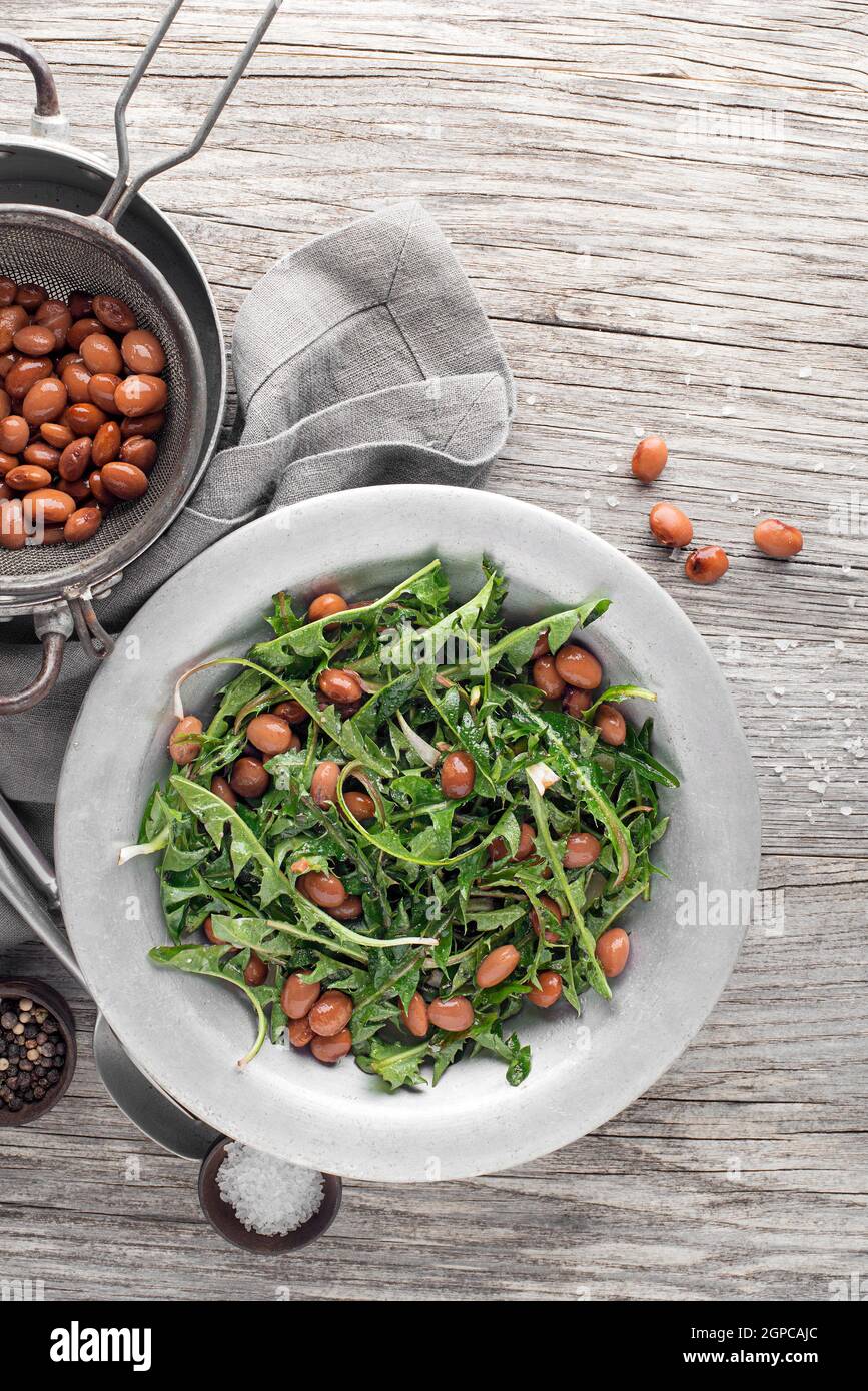 Salade de pissenlit frais avec des haricots sur fond de bois Banque D'Images