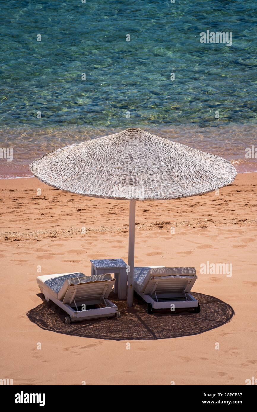 Plage de sable de luxe avec chaises de plage et parasol en paille blanche dans un complexe tropical sur la côte de la mer Rouge en Egypte, Afrique. Plages vides pendant la quarantaine Banque D'Images