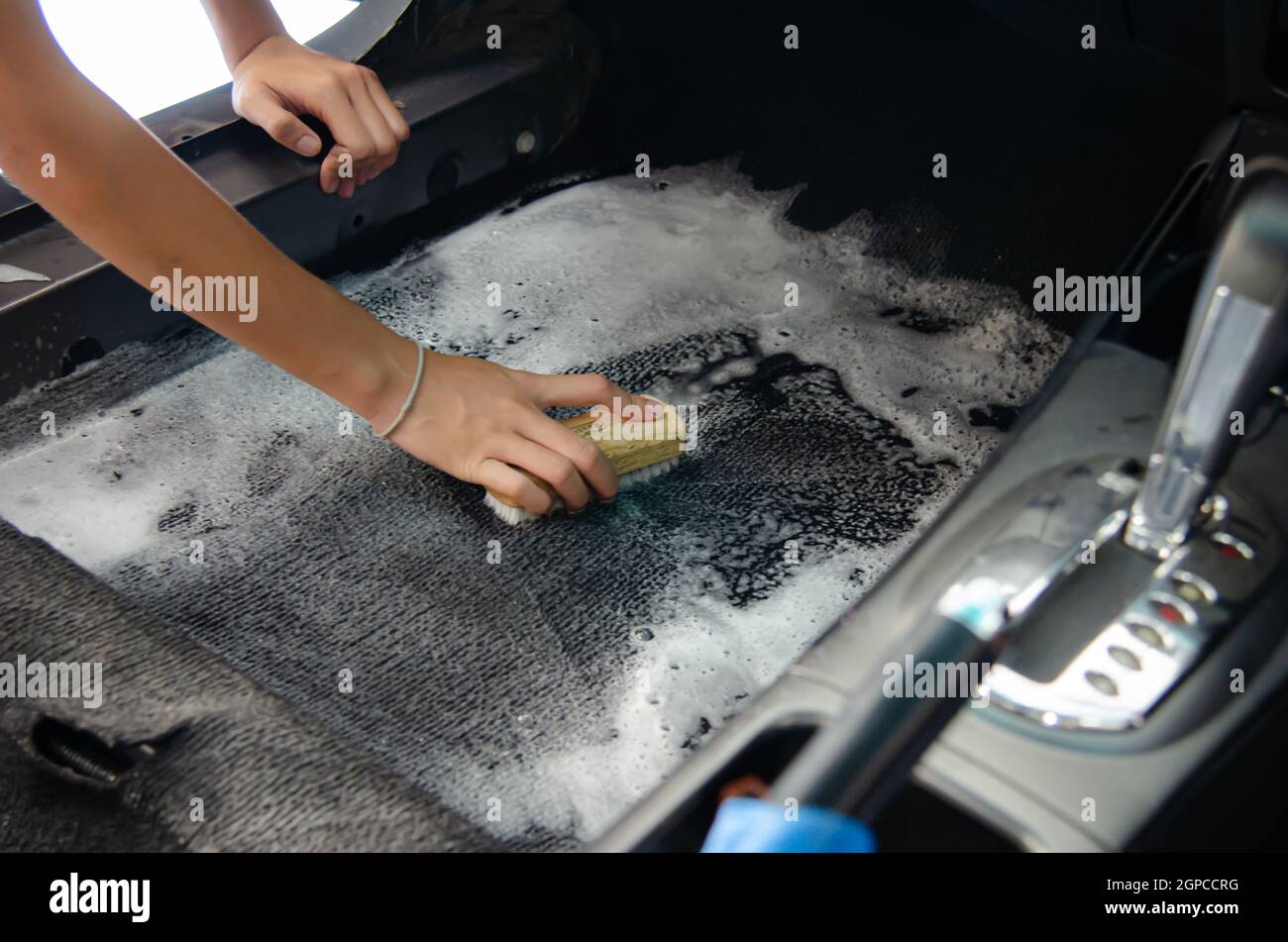 Laver le tapis de voiture.habillage à l'intérieur de la voiture moderne. nettoyer à l'aide d'une brosse et d'une solution de nettoyage sur le tapis  de voiture Photo Stock - Alamy