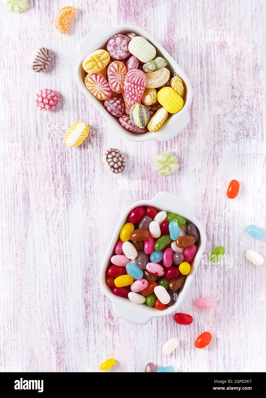 Vue de dessus des bonbons colorés et des jelly beans dans deux bols en céramique blanche. Concept de nourriture douce. Copier l'espace. Banque D'Images