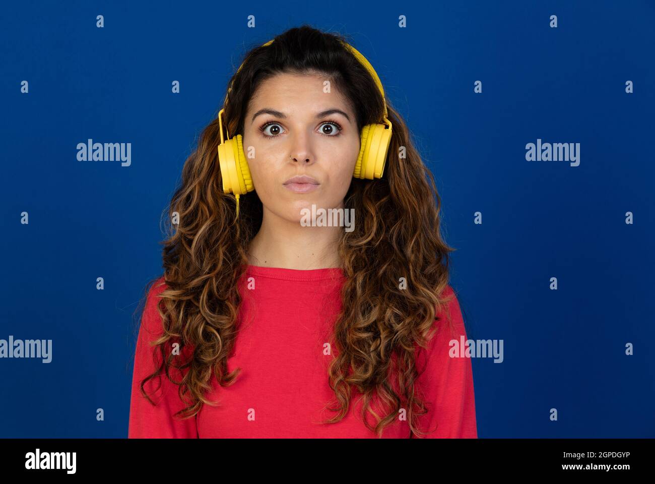 Portrait de la belle fille caucasienne avec cheveux bouclés et écouteurs écouter de la musique sur fond blanc Banque D'Images