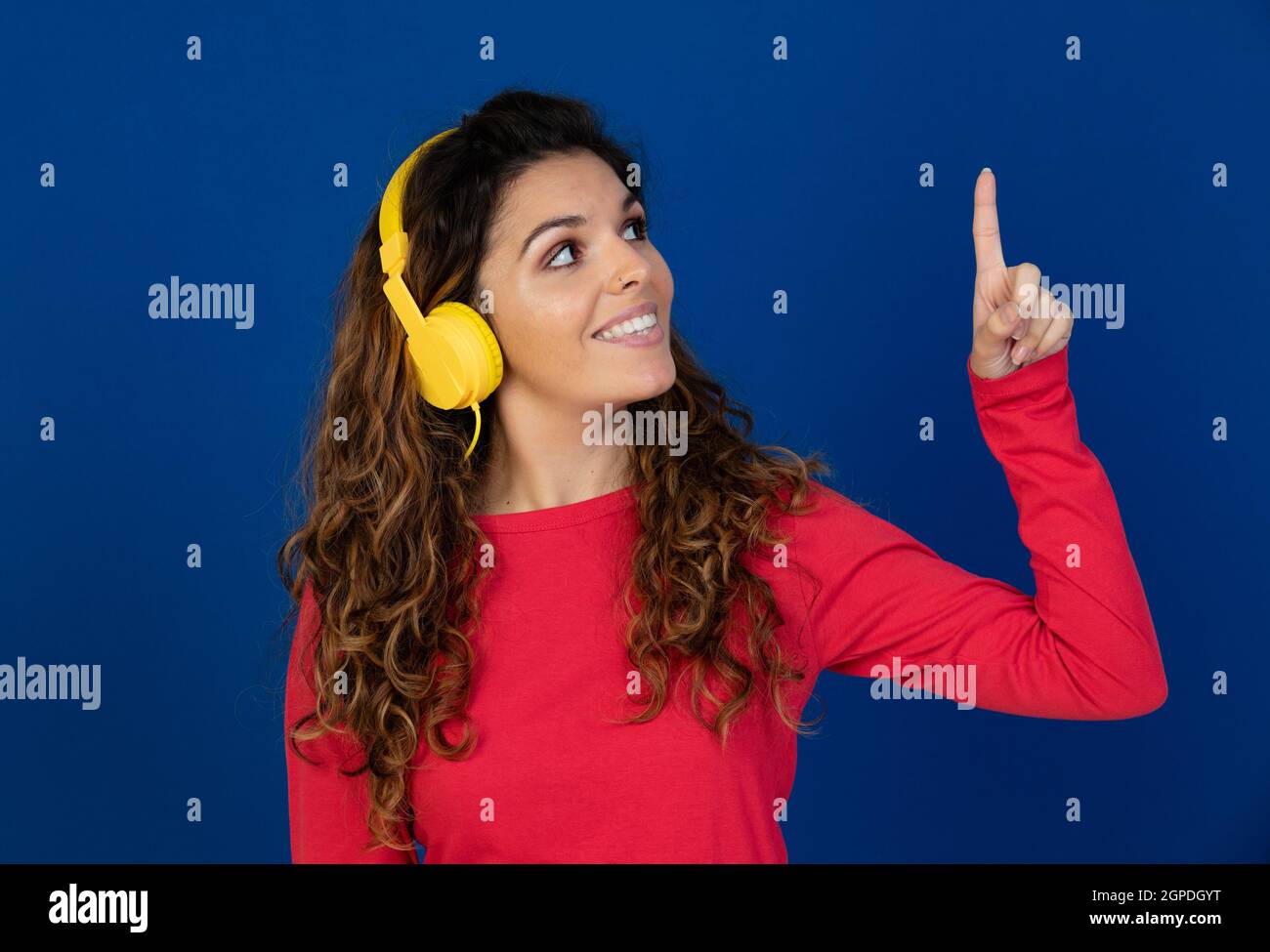 Portrait de la belle fille caucasienne avec cheveux bouclés et écouteurs écouter de la musique sur fond blanc Banque D'Images