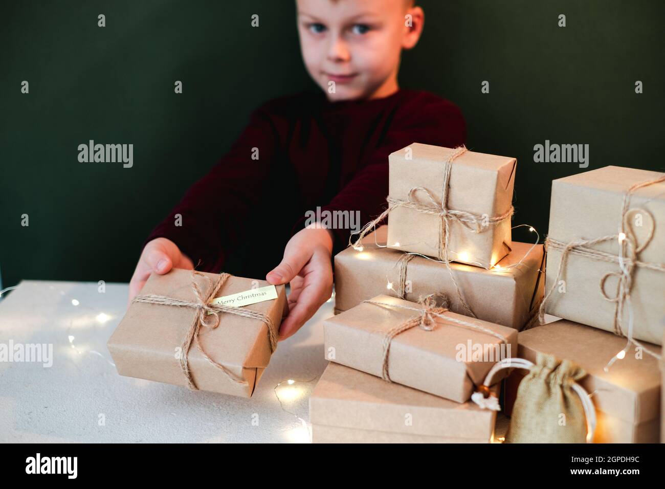 Enfant tenant un cadeau de Noël fait main enveloppé de papier Kraft. Nouveau concept d'année et de Noël sans gaspillage. Photo de haute qualité Banque D'Images