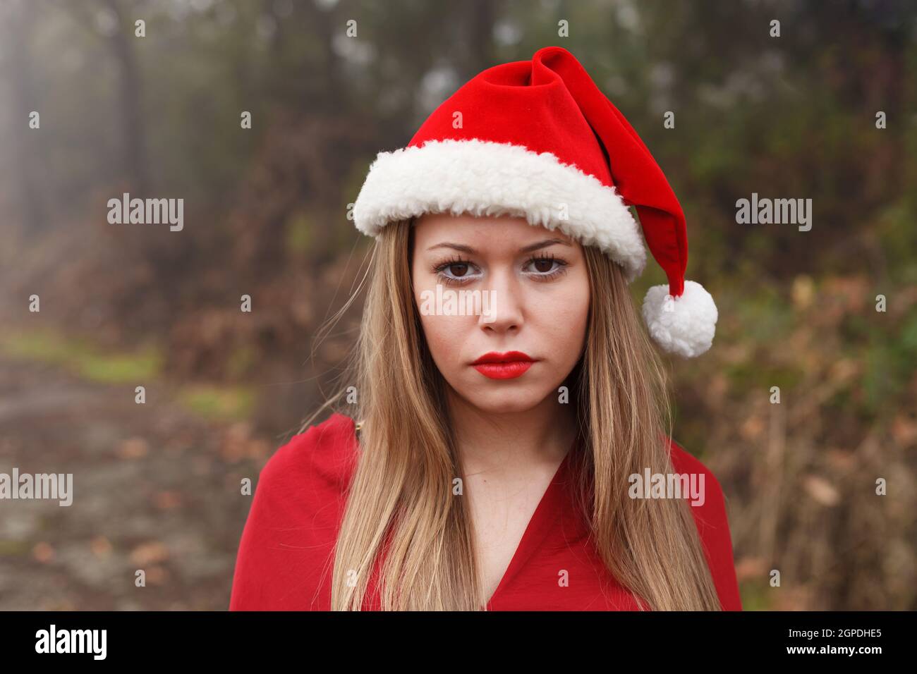 Jeune femme avec des lèvres rouges et chapeau de Noël dans la forêt Banque D'Images