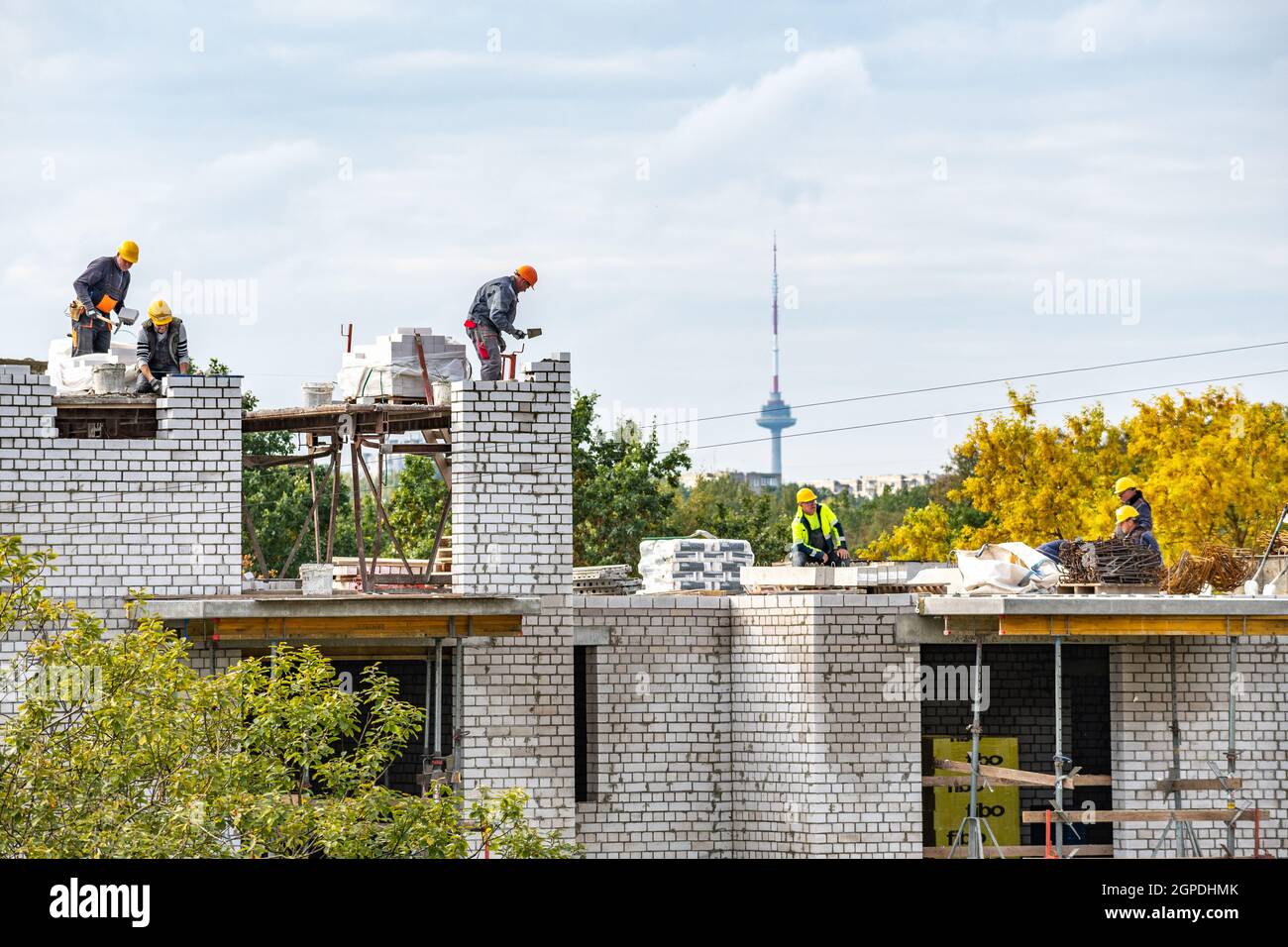 Vilnius, Lituanie - septembre 28 2021: Nouveaux bâtiments ou maisons en construction avec des travailleurs à l'œuvre contre le ciel nuageux avec la tour de télévision de Vilnius Banque D'Images