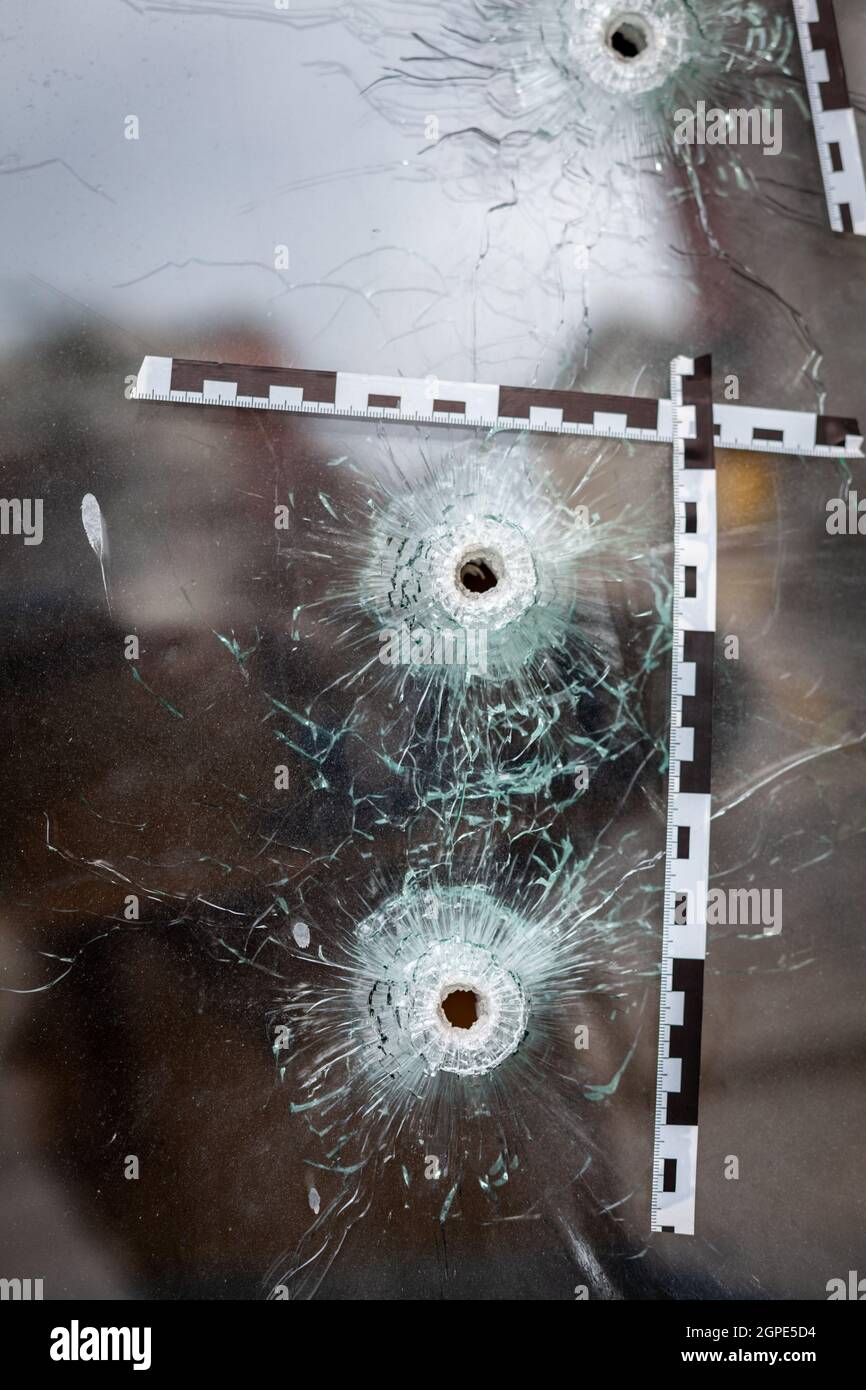 trous de balle dans une fenêtre d'atelier de verre marqués d'un ruban de police. Banque D'Images