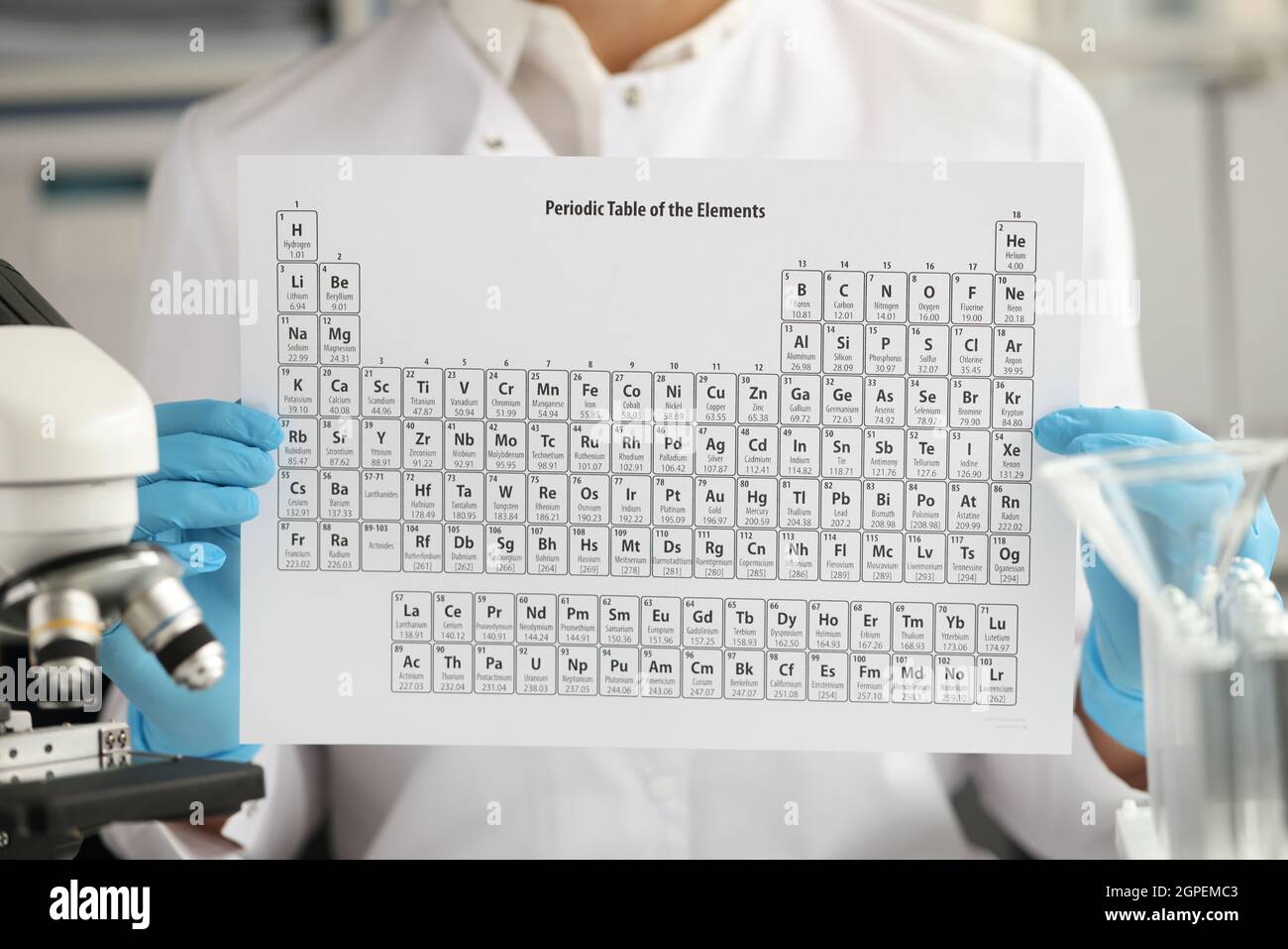 Le pharmacien ganté tient régulièrement le tableau des éléments chimiques en gros plan Banque D'Images