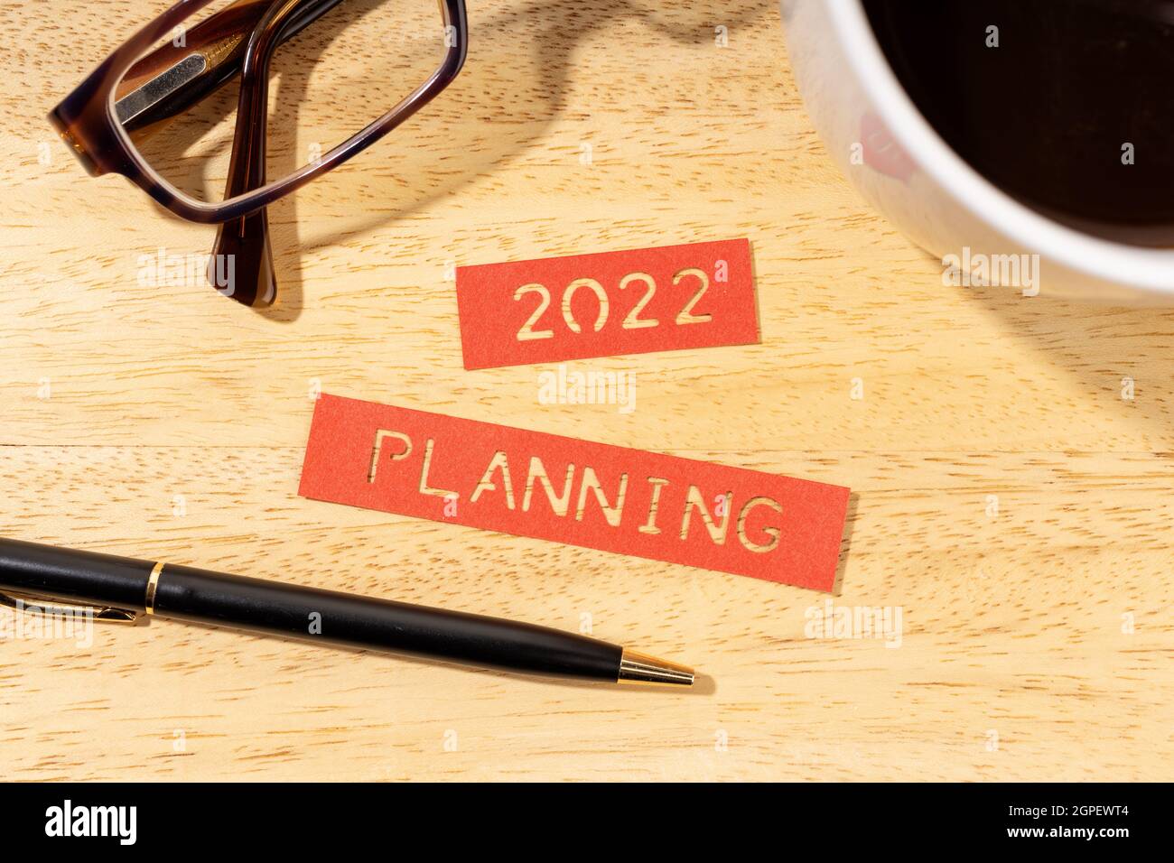 Concept de planification de la nouvelle année 2022. Étiquettes, stylo, tasse de café et lunettes sur bureau en bois Banque D'Images