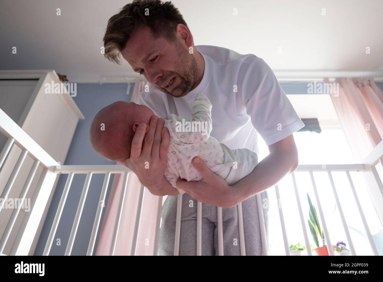 Le jeune père tente de calmer son nouveau-né en la tenant entre ses mains. Banque D'Images