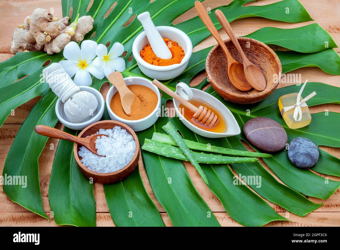 Feuilles vertes avec ingrédient nature spa poudre de curcuma en mortier  blanc ,le gingembre,herbal compress ball,savon,miel,Poudre de cannelle ,bol  en bois ,maisons s Photo Stock - Alamy