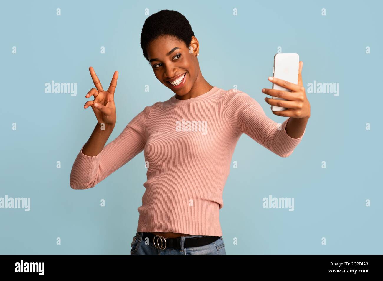 Joyeuse jeune Black Femme prenant Selfie sur smartphone et montrant le geste de paix Banque D'Images