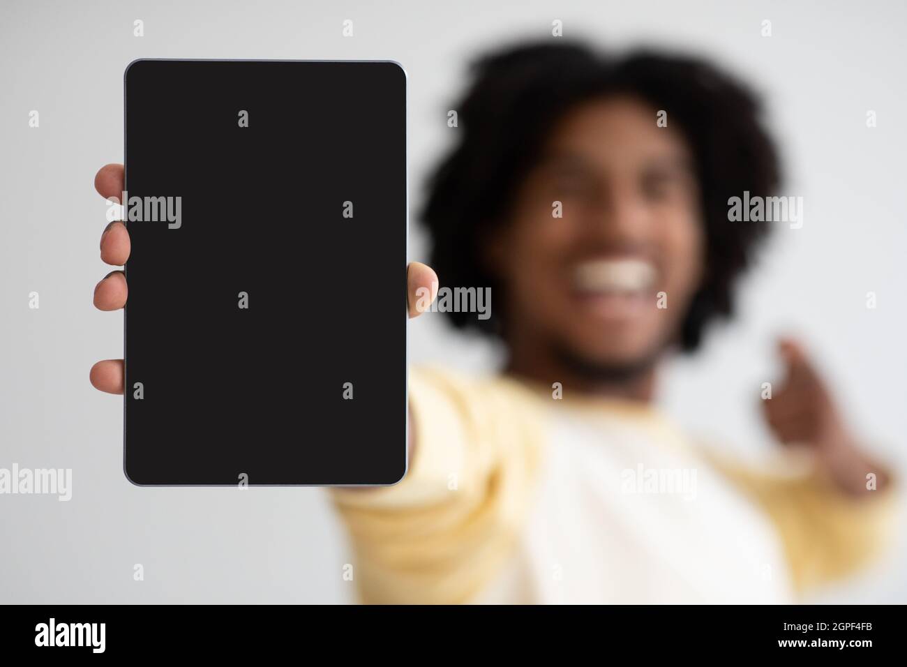 Joyeux Black Guy montrant et pointant vers la tablette numérique avec écran vide Banque D'Images