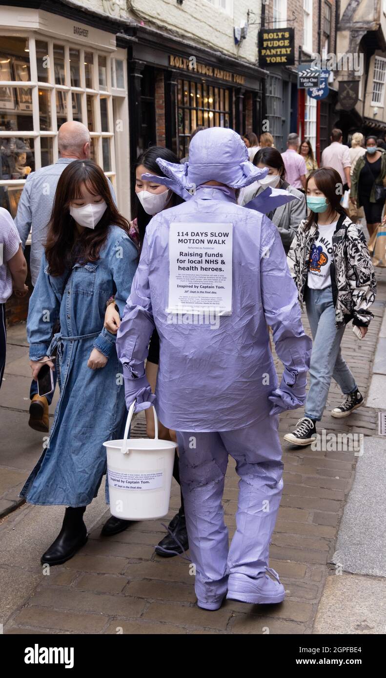 Un travailleur de charité au Royaume-Uni; un homme qui travaille pour recueillir de l'argent pour le NHS en faisant une marche lente; portant un seau de charité, The Shambles, York au Royaume-Uni Banque D'Images