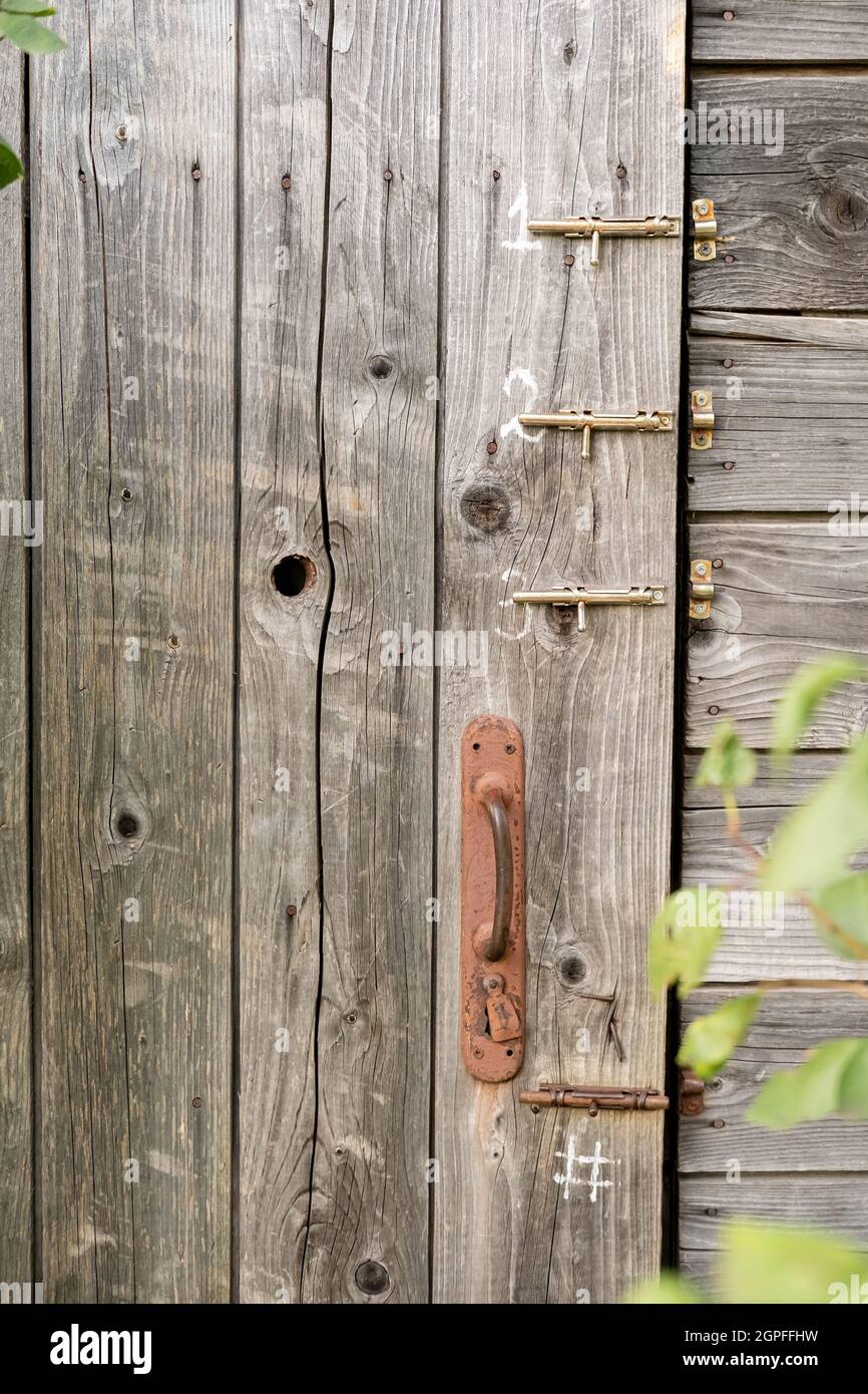 Porte d'une ancienne toilette en bois ou d'une ancienne grange avec une  porte rouillée et trois loquets, dans une campagne Photo Stock - Alamy