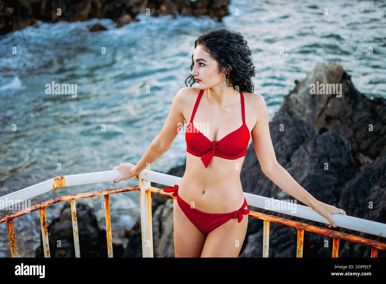 jeune femme posant avec le bikini rouge sur les rambardes de plage Banque D'Images