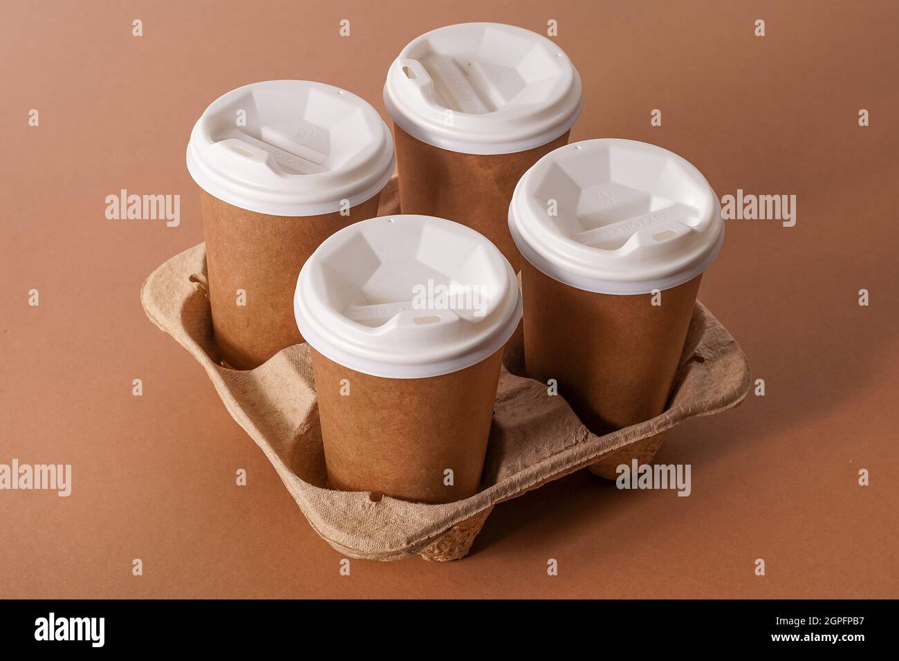 Gobelets en papier dans un porte-gobelet pour le café à emporter.Gobelet en papier avec une boisson.Vaisselle jetable.Carton écologique recyclable.Arrière-plan marron.Copier l'espace.Livraison du petit déjeuner à la réception. Banque D'Images