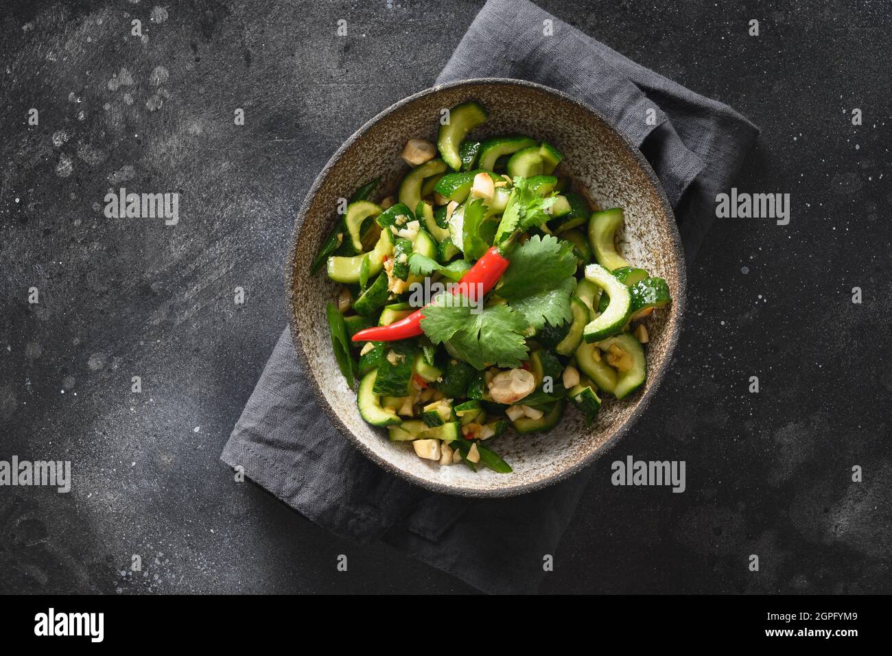 Salade asiatique épicée de concombre avec coriandre fraîche, gingembre, piment, vinaigre noir sur fond noir. Concombres épicés. Populaire chinois appe Banque D'Images