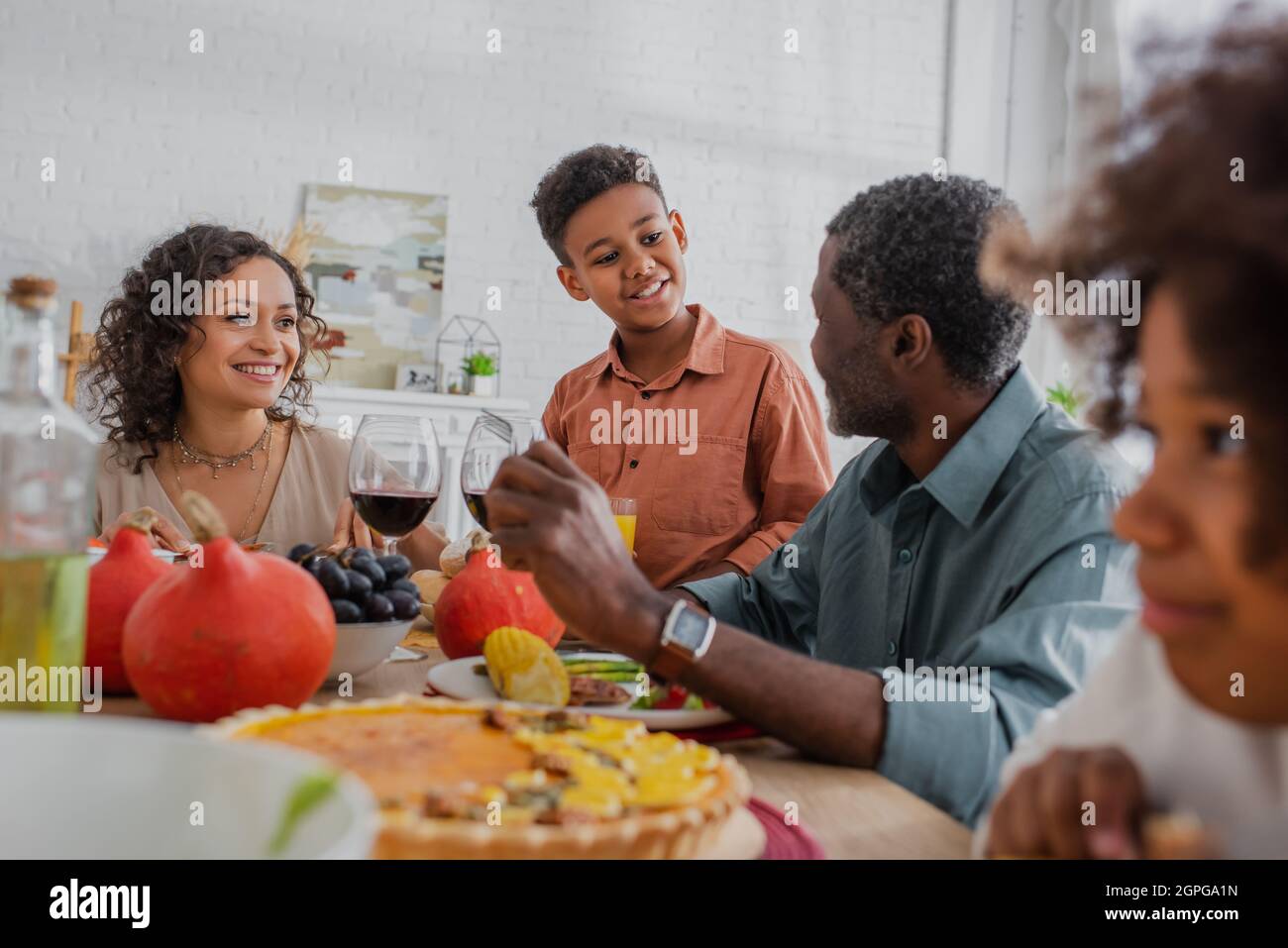 un garçon afro-américain souriant parle au grand-père lors d'un dîner d'action de grâce en famille Banque D'Images