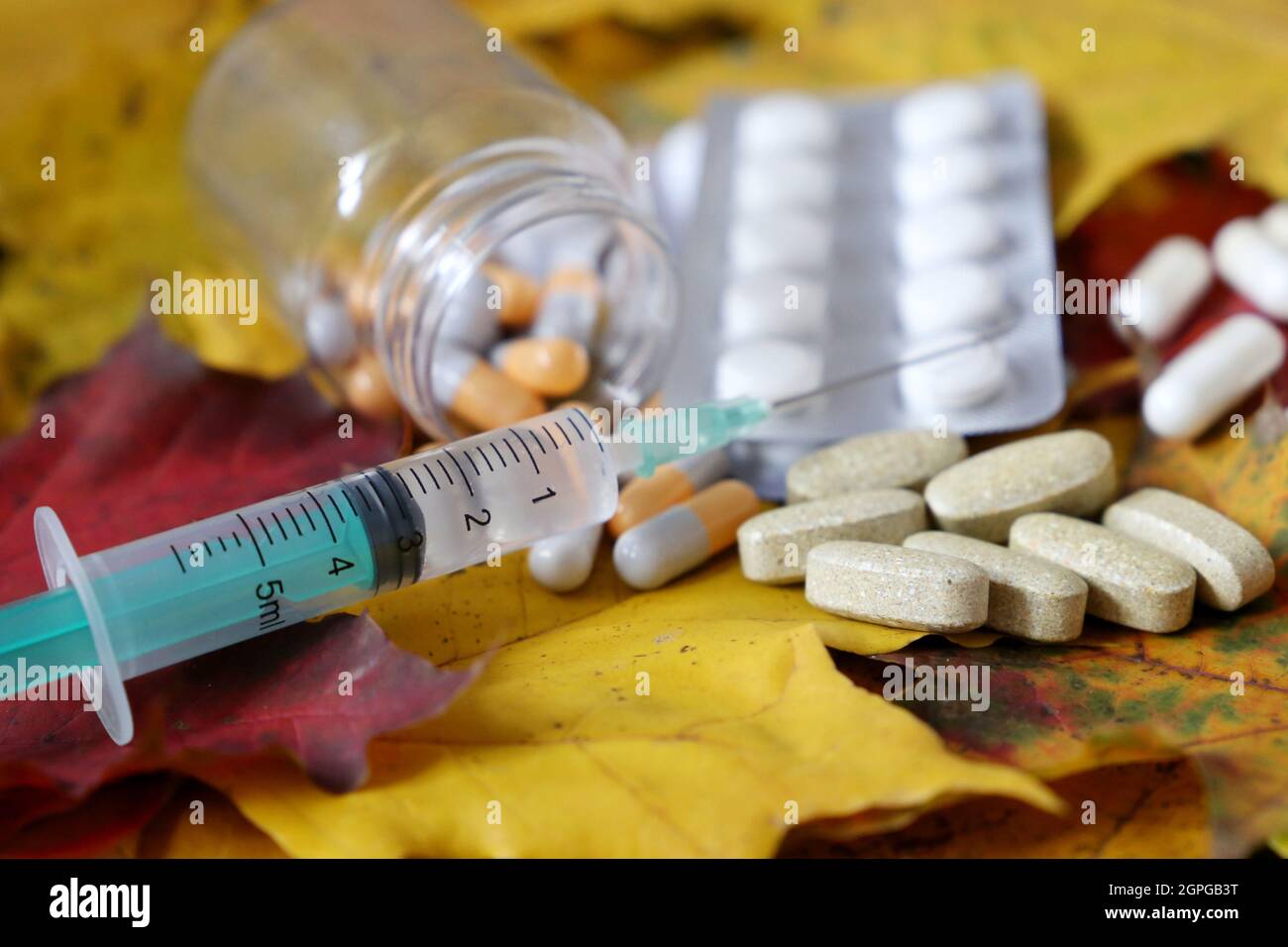 Seringue et pilules sur les feuilles d'érable d'automne. Soins de santé pendant la saison du rhume et de la grippe Banque D'Images