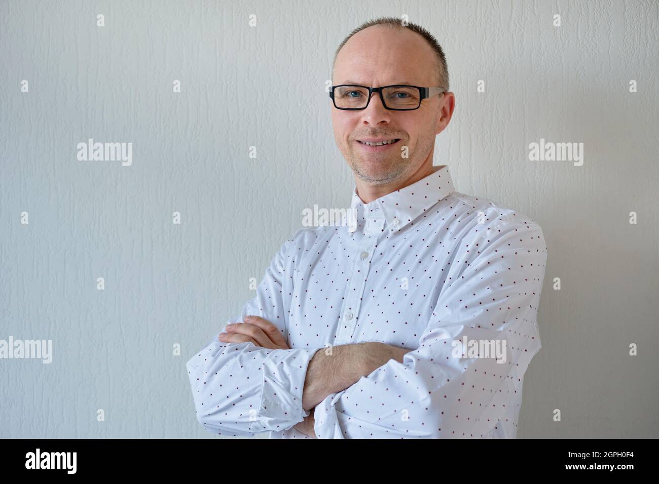 Vue en demi-longueur d'un homme souriant et non rasé.Un homme d'âge moyen avec des lunettes se tient contre un fond blanc.La photo inclut un espace de copie Banque D'Images