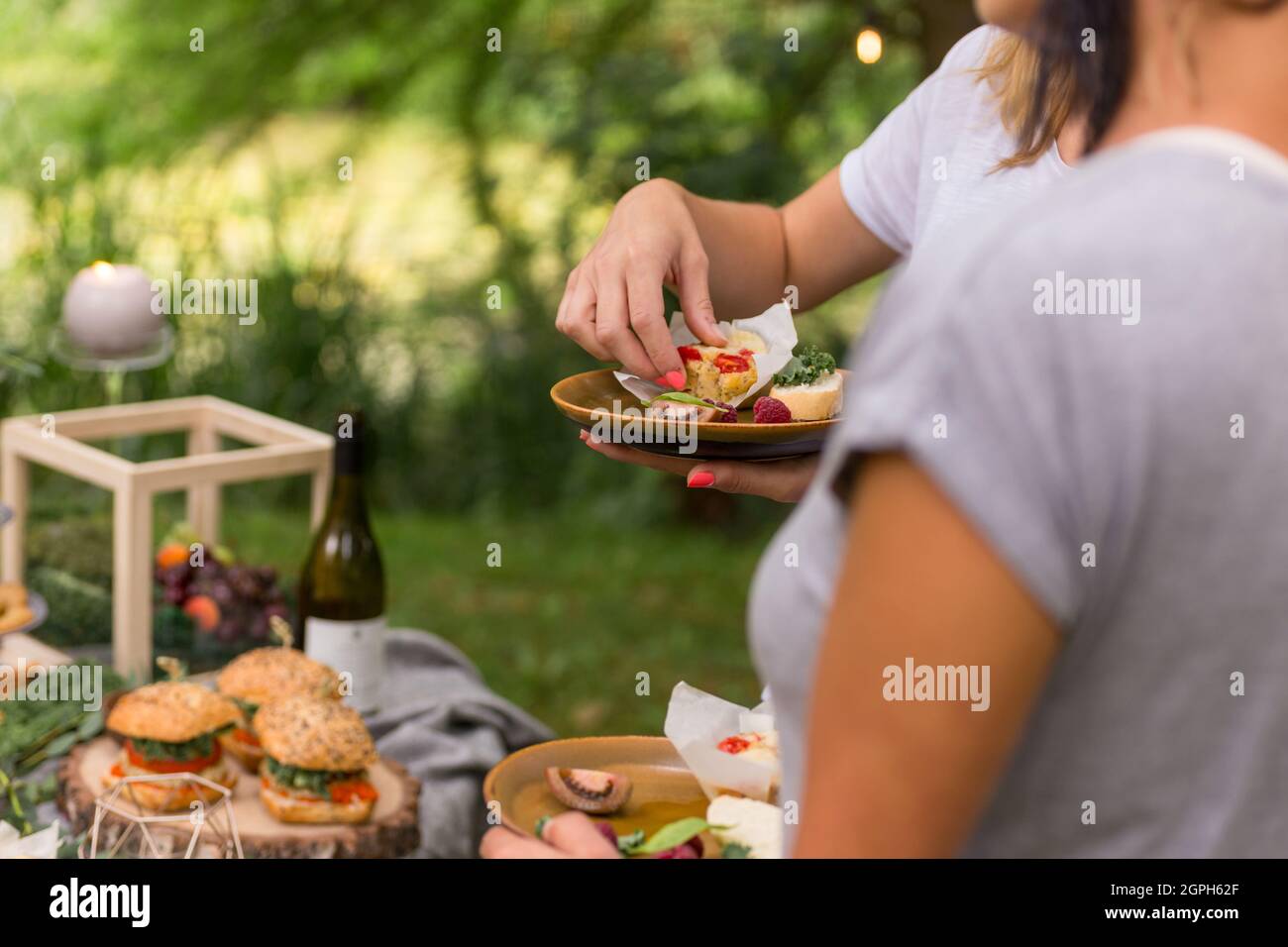 Des femmes anonymes tenant des assiettes et drinksat partie de jardin informelle. Naturel. Image de style de vie. Banque D'Images