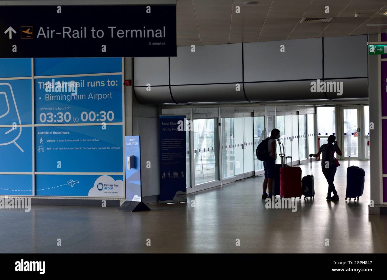 À l'intérieur de la gare internationale de Birmingham, passagers en silhouette avec des sacs allant au système 'Air-Rail Link' Banque D'Images