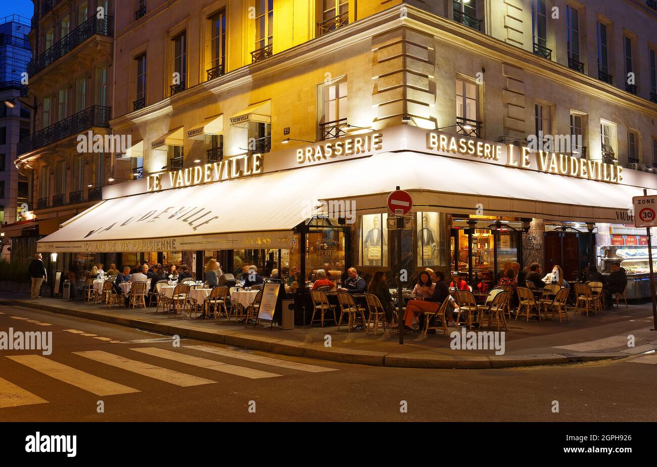 La cuisine française brasserie Le vaudeville la nuit. Il est situé près de palais Brogniart à Paris, France. Banque D'Images