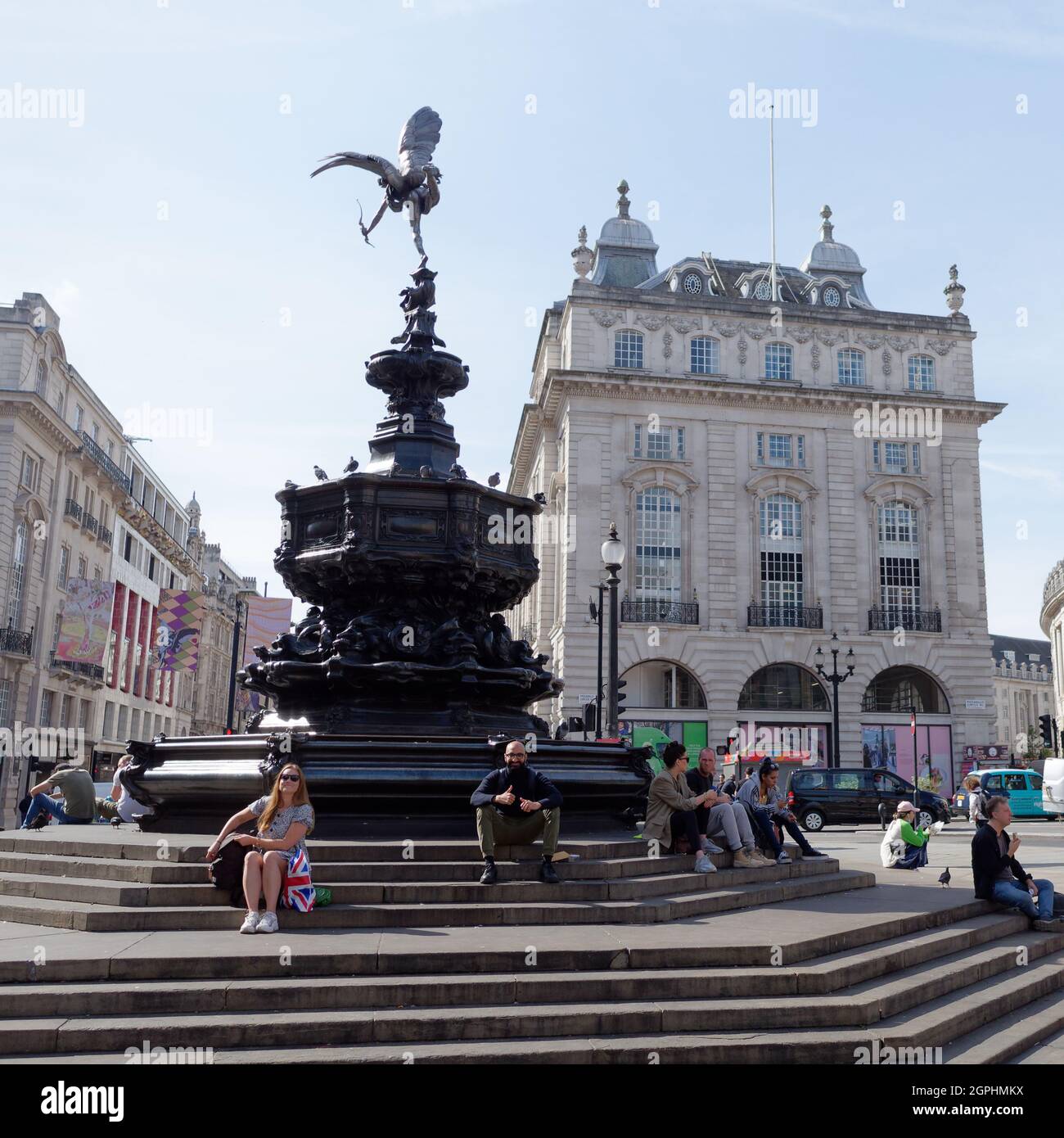 Londres, Grand Londres, Angleterre, 21 septembre 2021 : Tourses, assis et sourire, et chat sur la fontaine commémorative Shaftesbury alias Eros dans Piccadilly Circus. Banque D'Images