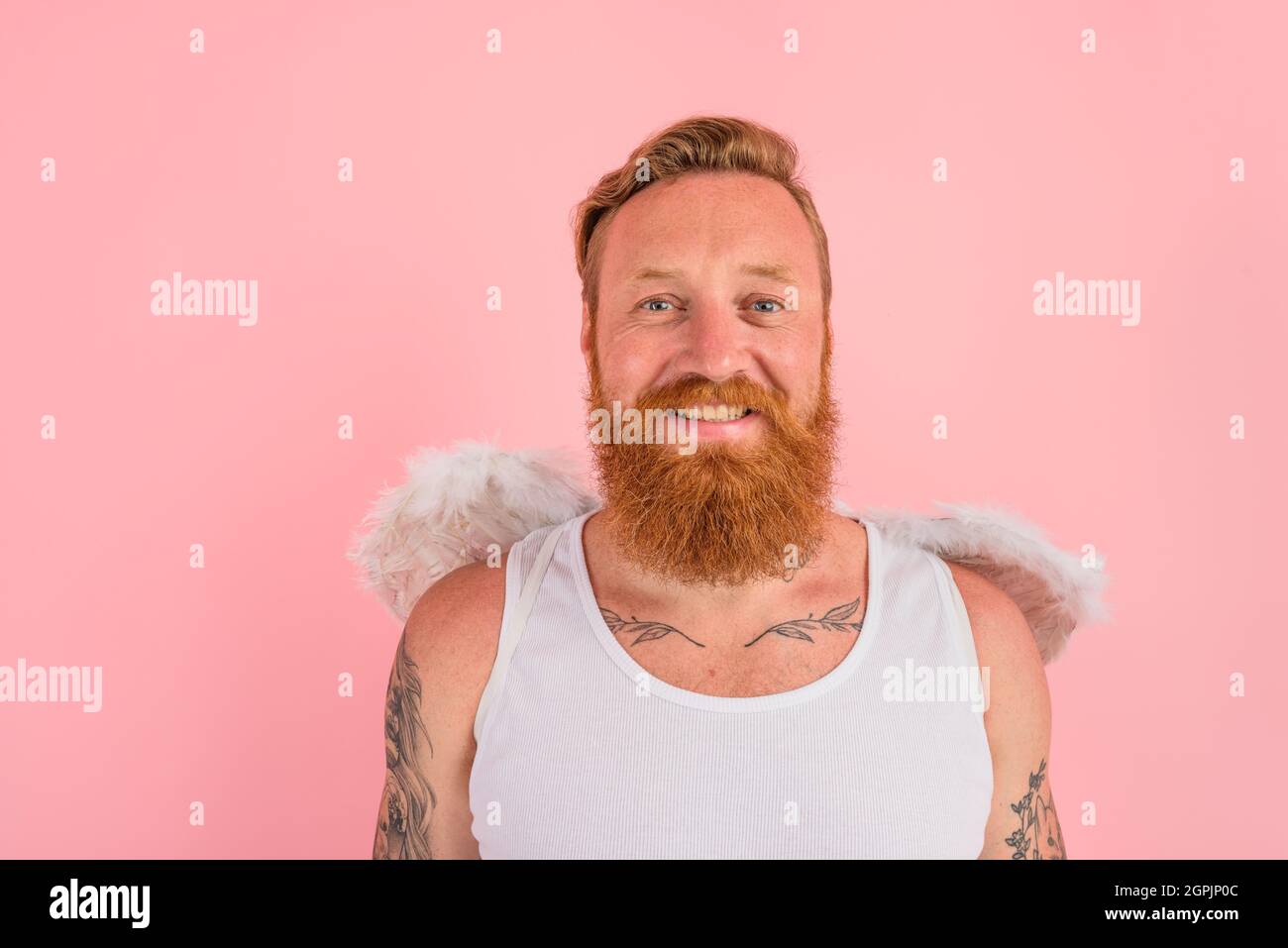 L'homme heureux avec la barbe et les tatouages agit comme un ange Banque D'Images