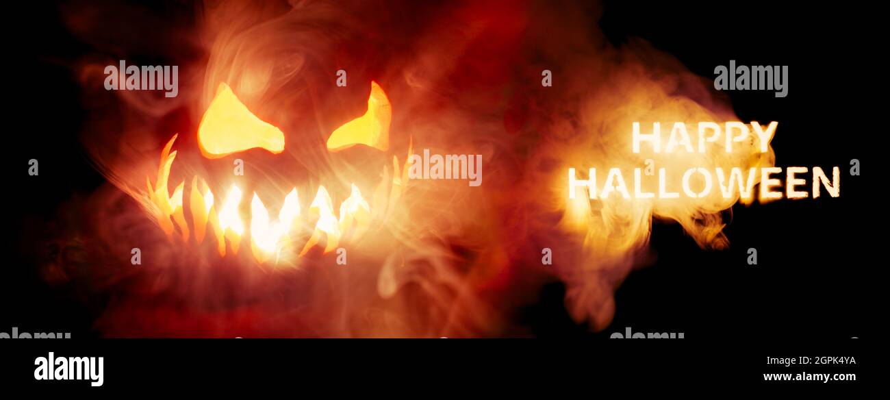 Joyeux texte Halloween et effrayant Jack o lanterne visage lumineux dans la fumée et le feu. Banque D'Images