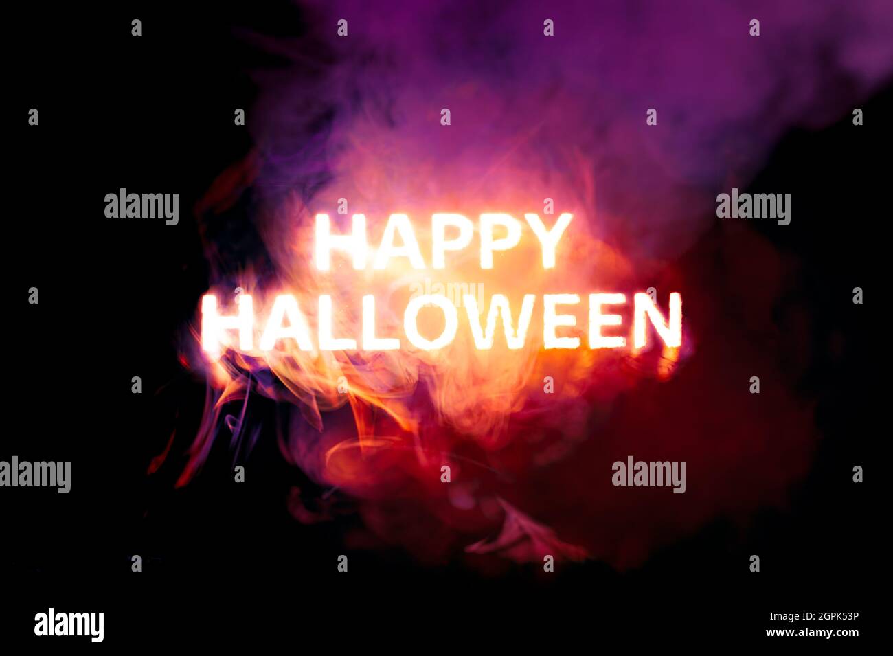 Texte brillant heureux Halloween brûlant rouge, orange, et violet fumée Banque D'Images